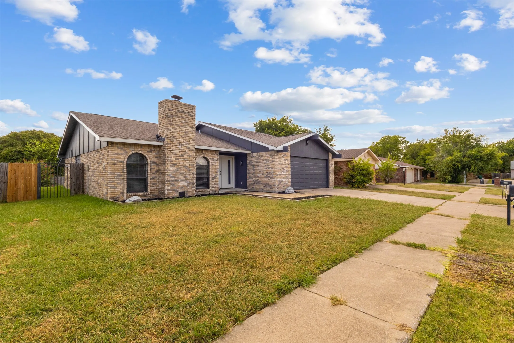Brick facade with an arched window, integrated garage, and a side fence