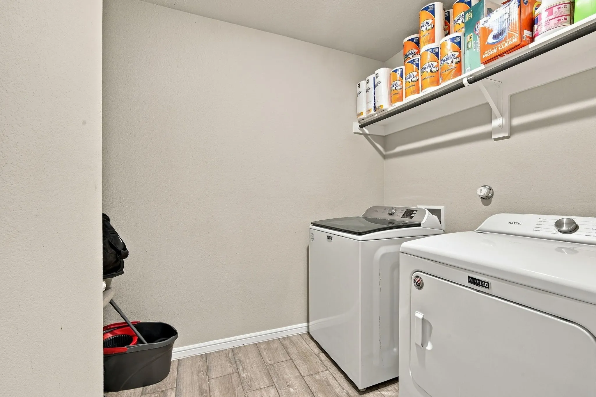 Laundry area featuring wood-finish flooring, built-in shelving, and a hanging rod