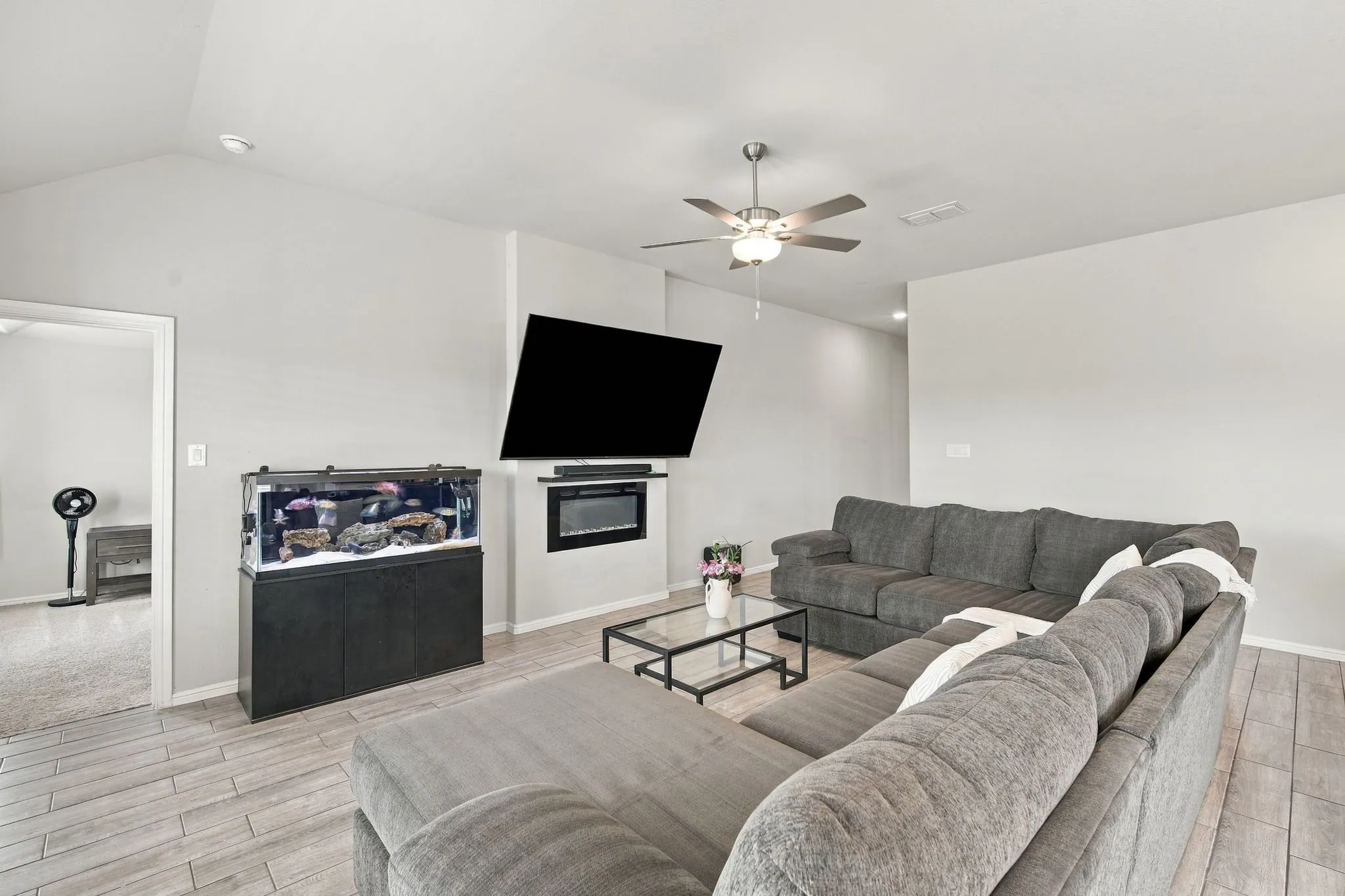 Vaulted ceiling, ceiling fan with light fixture, wood-finish flooring, built-in electric fireplace, recessed lighting