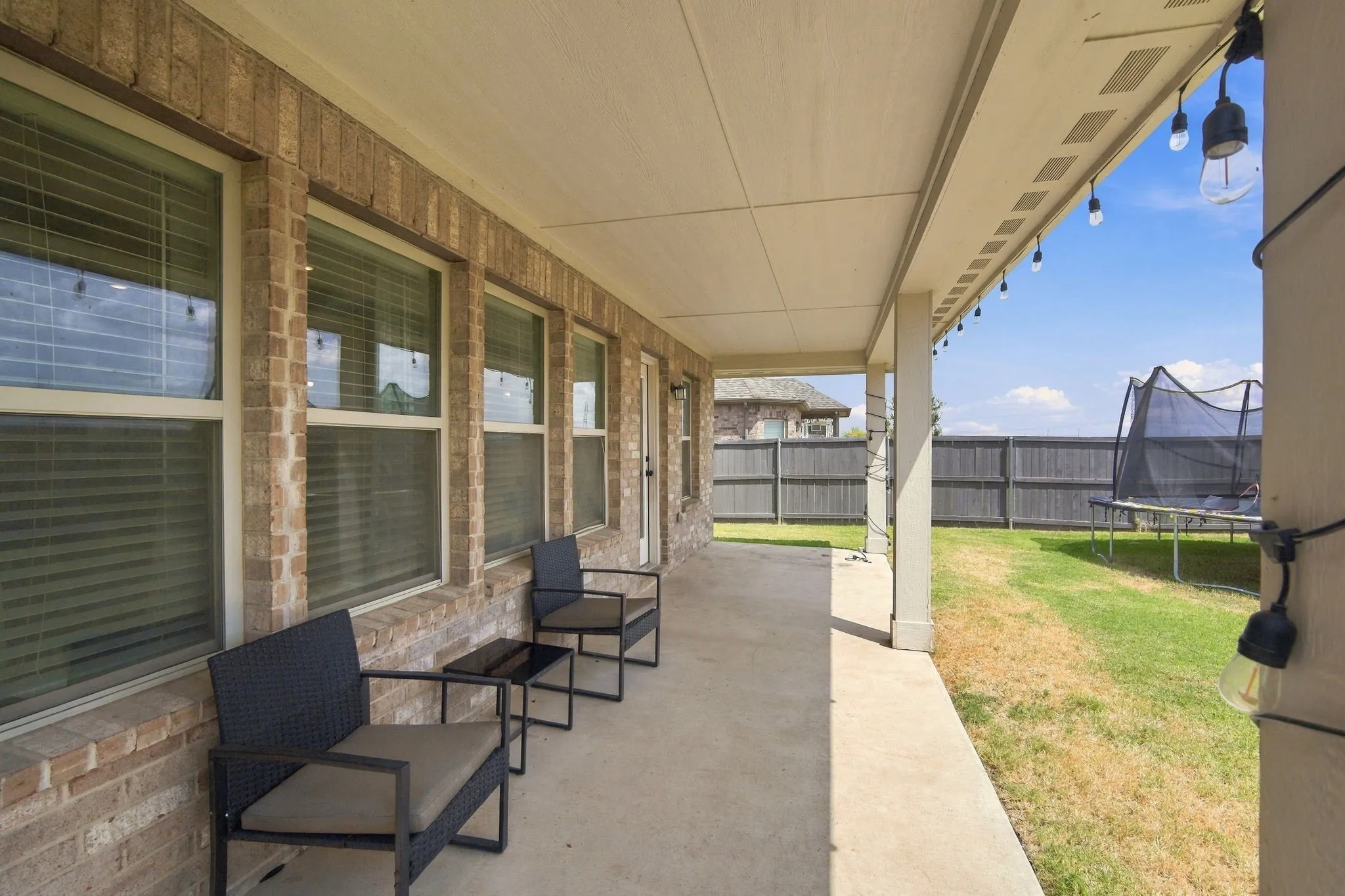 Covered patio with a concrete surface, brick exterior, and multiple windows