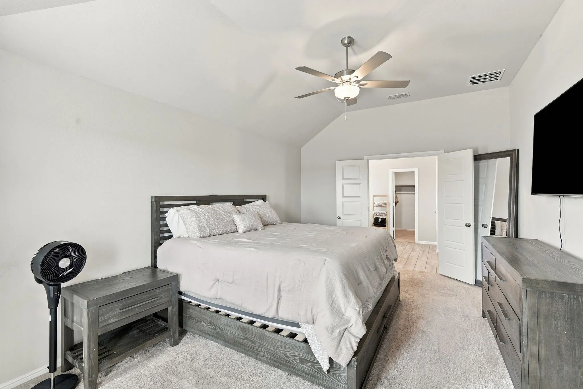 Vaulted ceiling with a ceiling fan, light-toned carpeting, and a built-in closet with wood-finish flooring