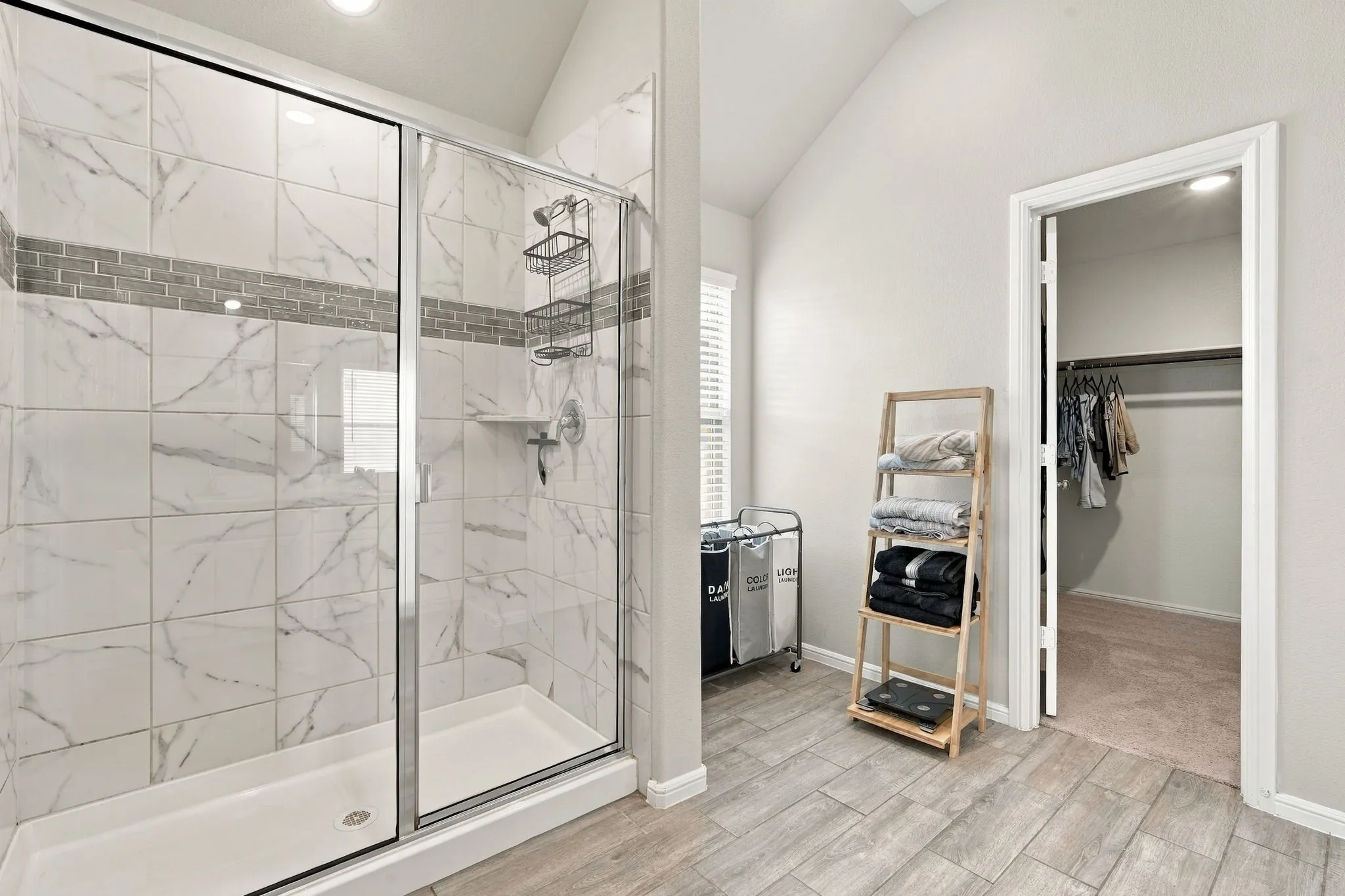 Glass-enclosed shower with tiled walls and a decorative mosaic accent band