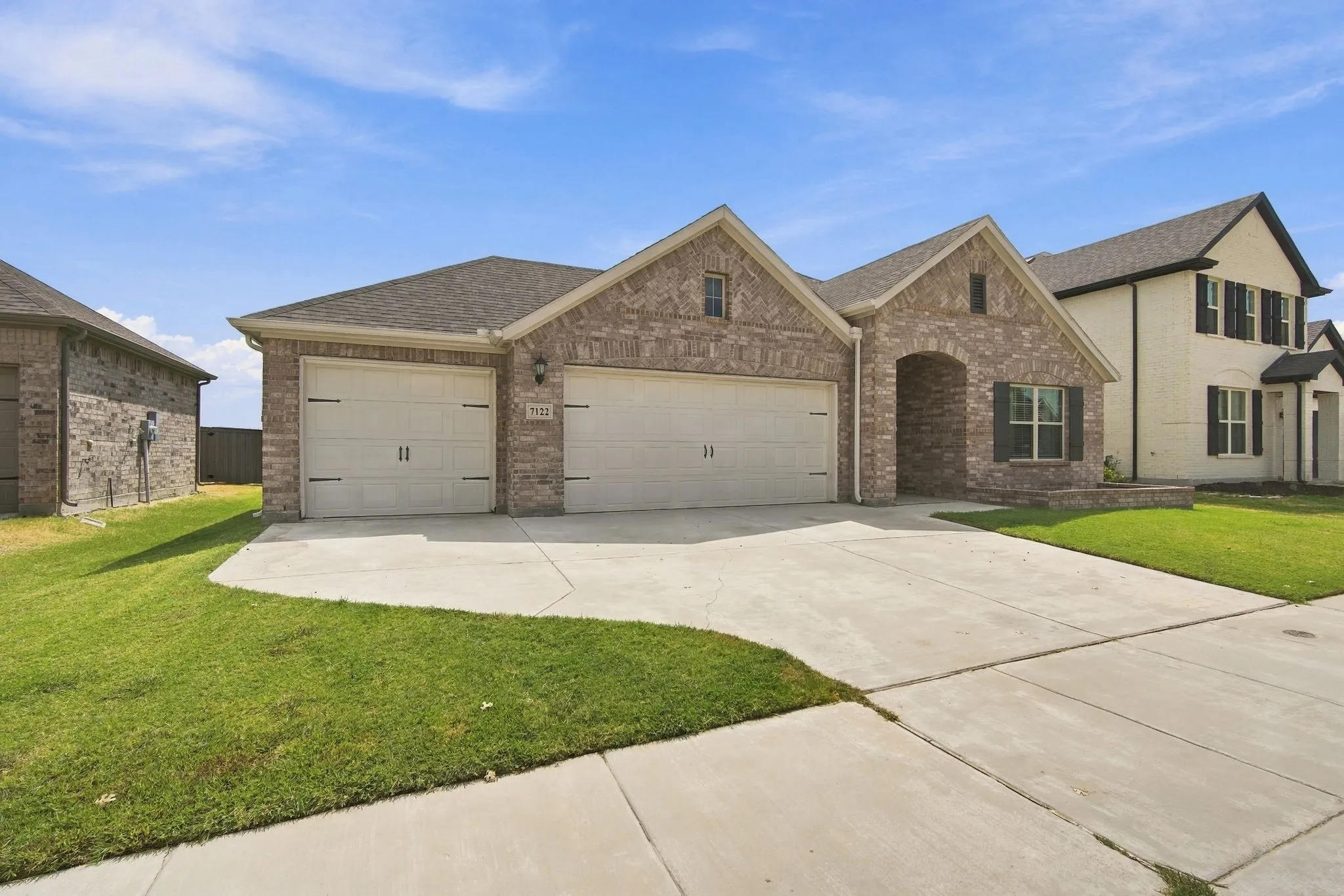 Brick exterior with an arched entryway, two-car garage, and concrete driveway