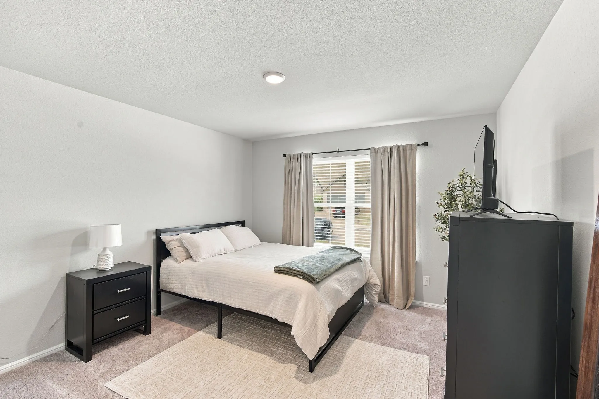 Wall-to-wall carpeting and a window with blinds and drapes