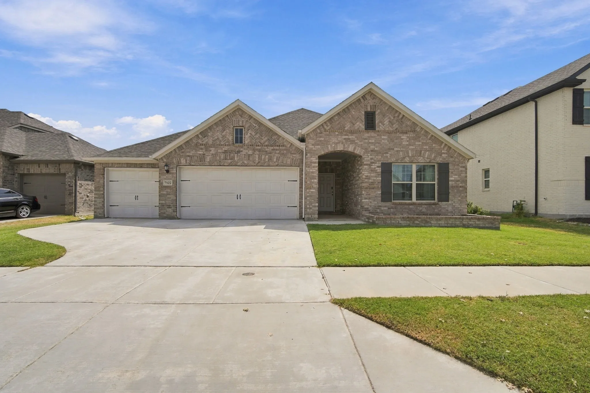 Brick facade with gabled roof lines, attached two-car garage, and an arched entry
