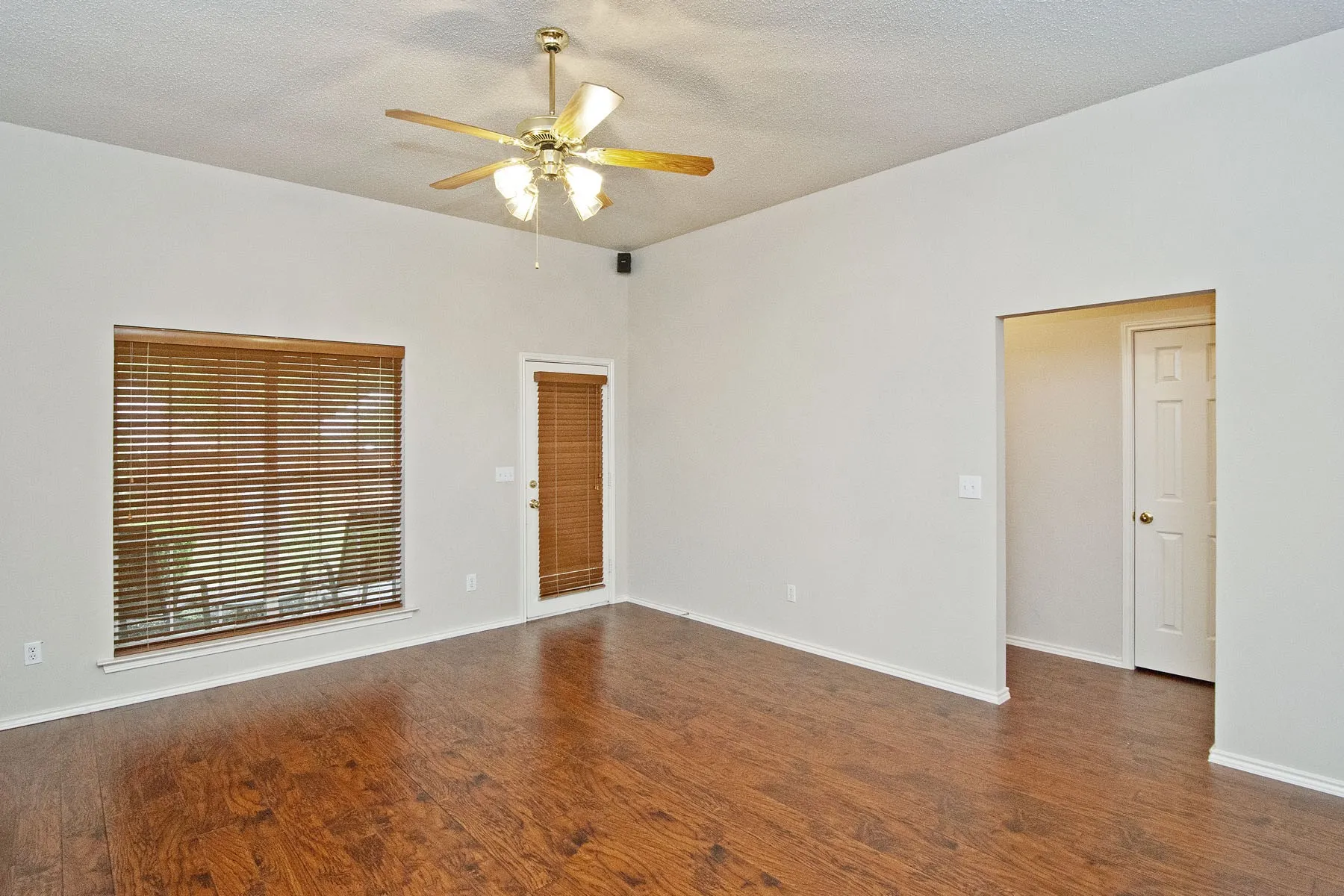 Unfurnished room with a textured ceiling, wood finished floors, and a ceiling fan