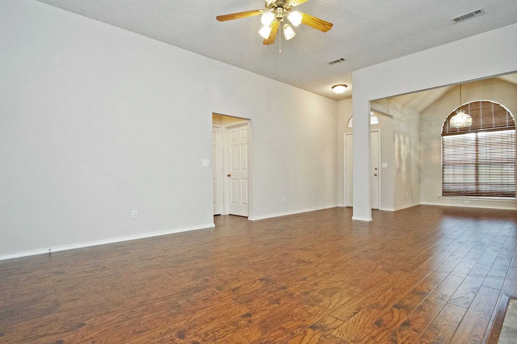 Unfurnished room featuring dark wood-style floors, baseboards, ceiling fan, and visible vents