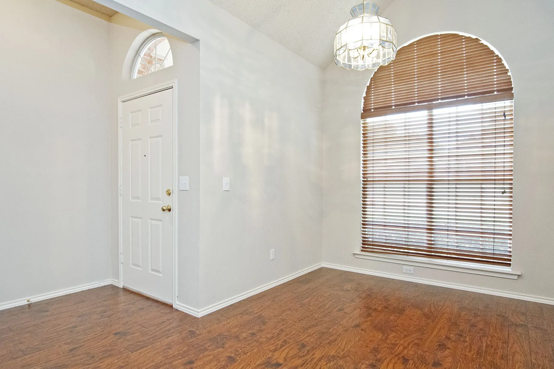 Foyer entrance featuring baseboards, wood finished floors, and an inviting chandelier