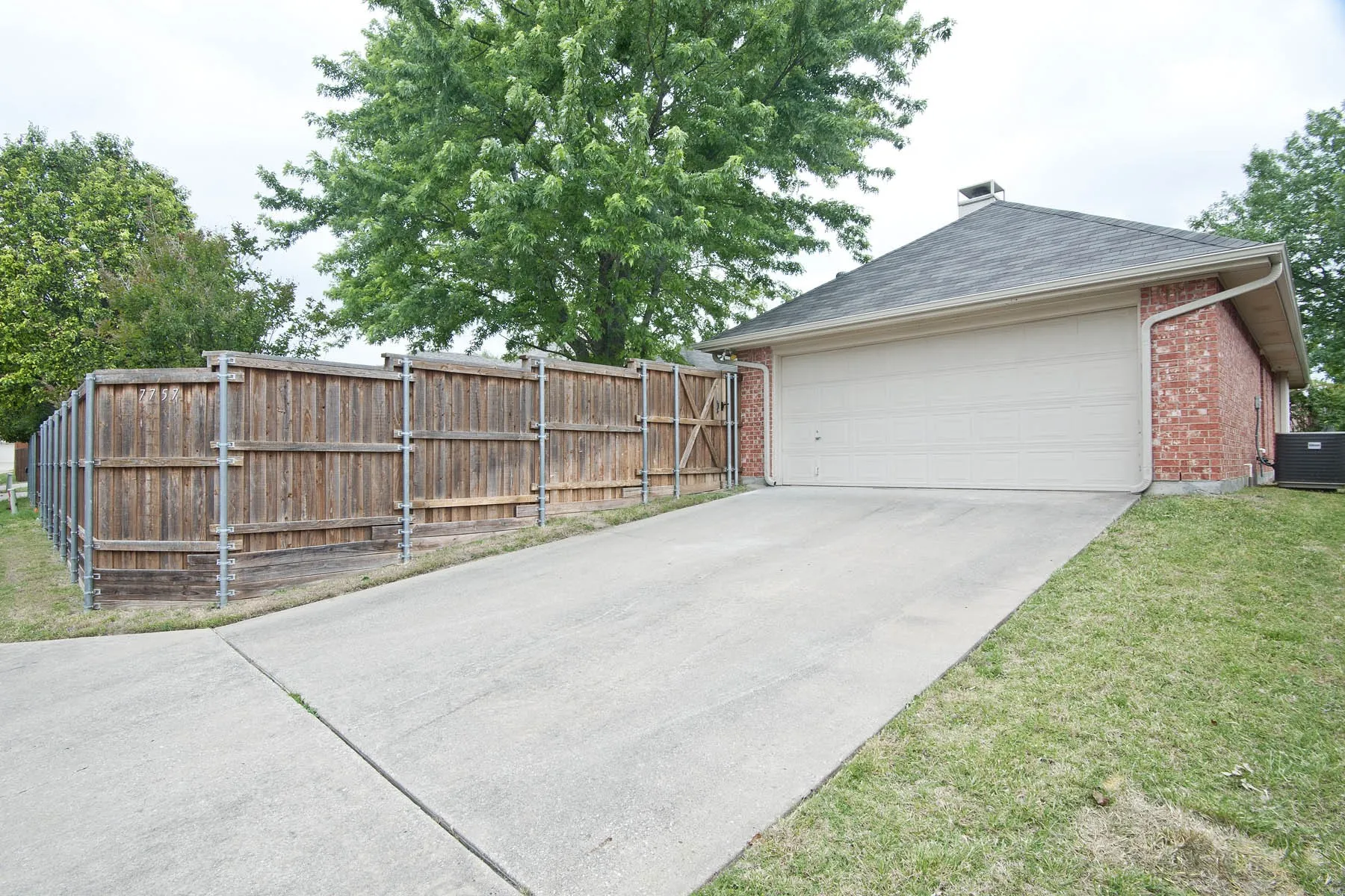 Garage featuring fence, central AC, and concrete driveway