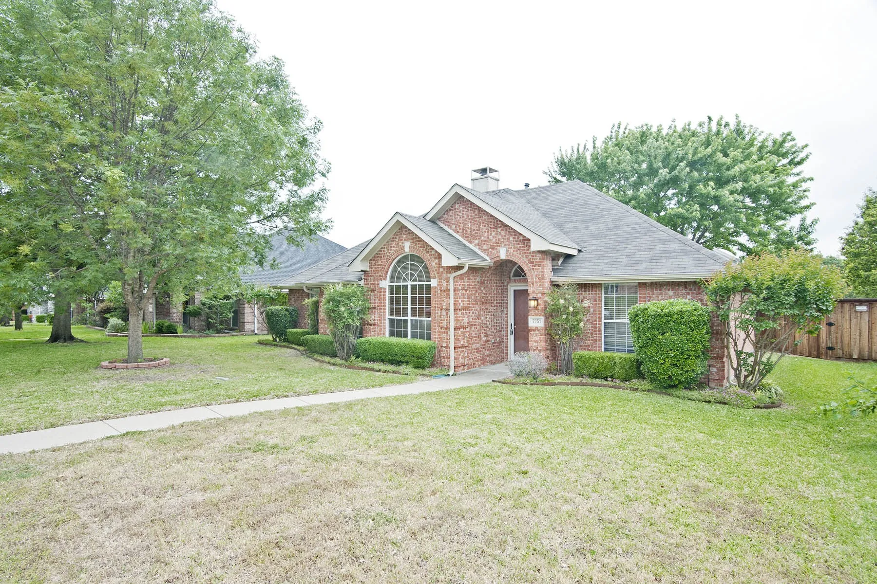 View of front of home featuring fence, a chimney, a front yard, brick siding, and a shingled roof