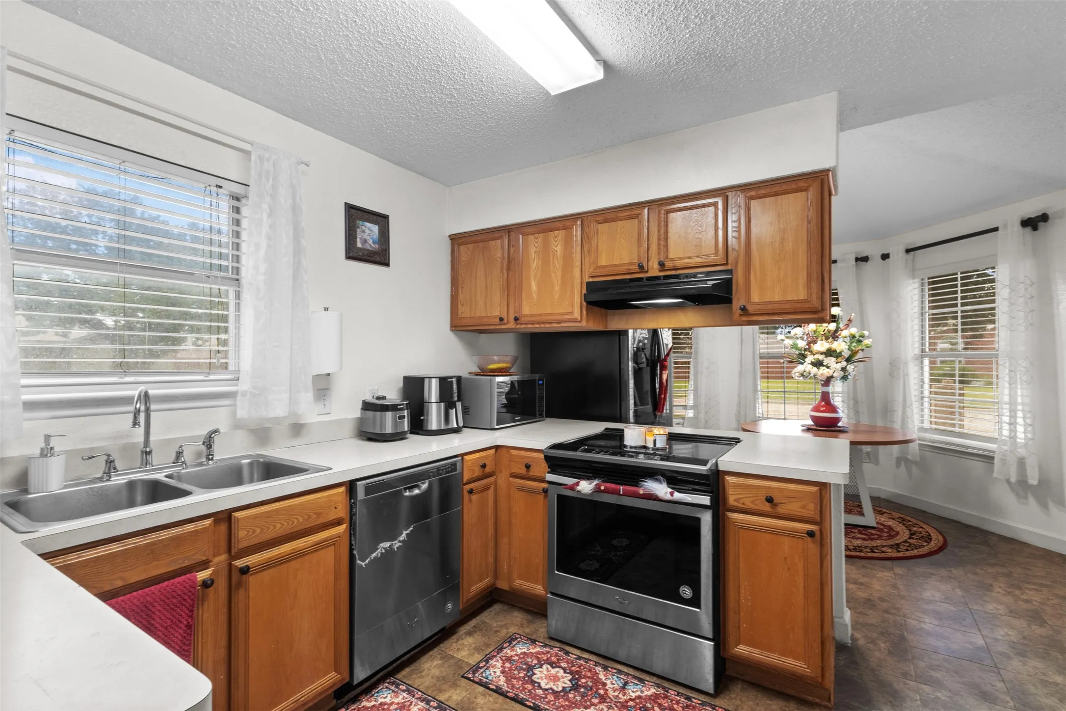 Kitchen featuring wood cabinetry, stainless steel appliances, a double basin sink, and laminate countertops