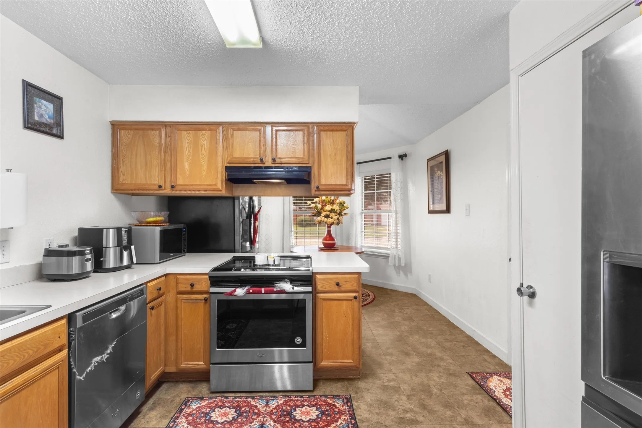Kitchen featuring wood cabinetry, stainless steel appliances, solid surface countertops, and an integrated window
