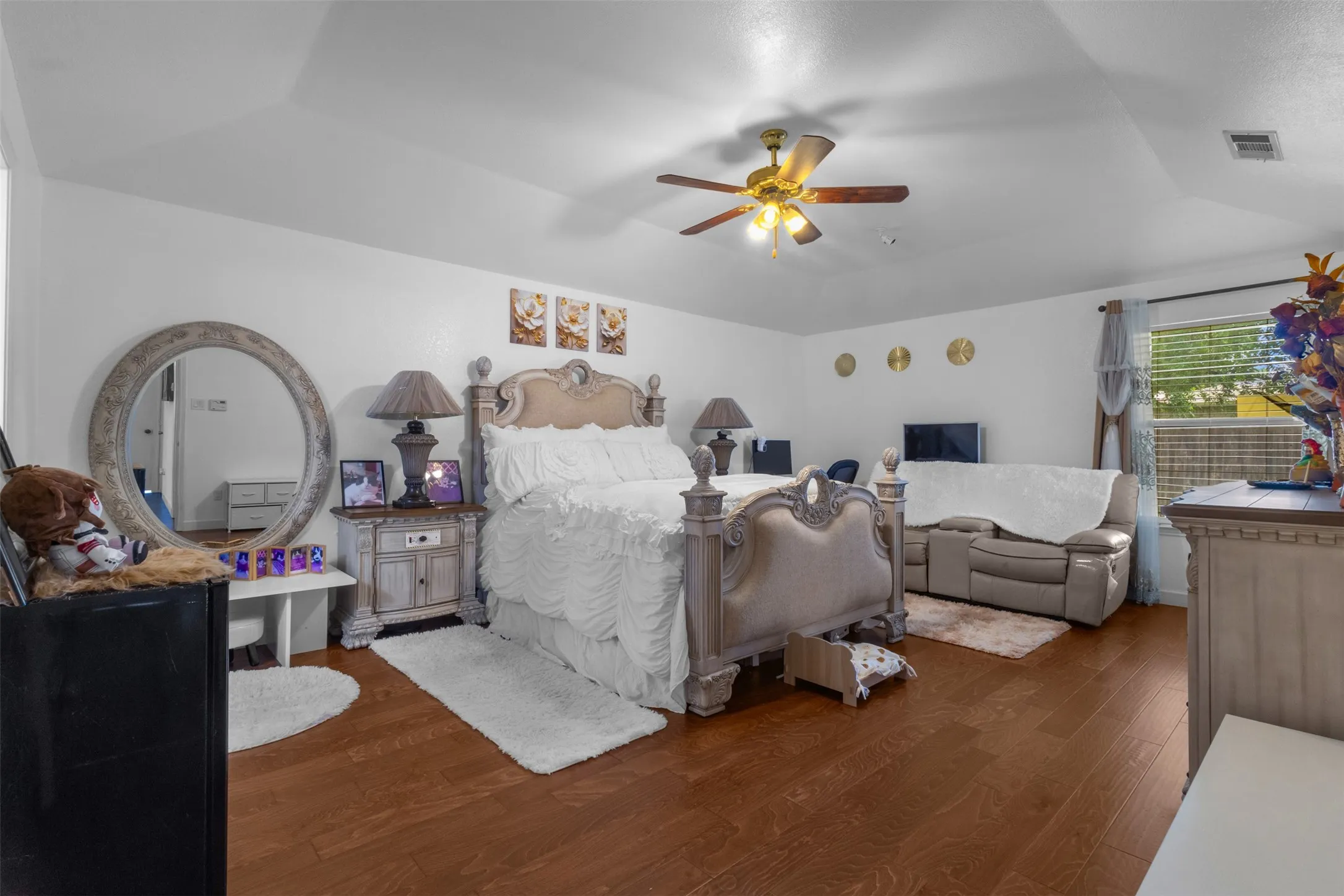 Spacious room with wood-finish flooring, a tray ceiling, and a ceiling fan with integrated lighting