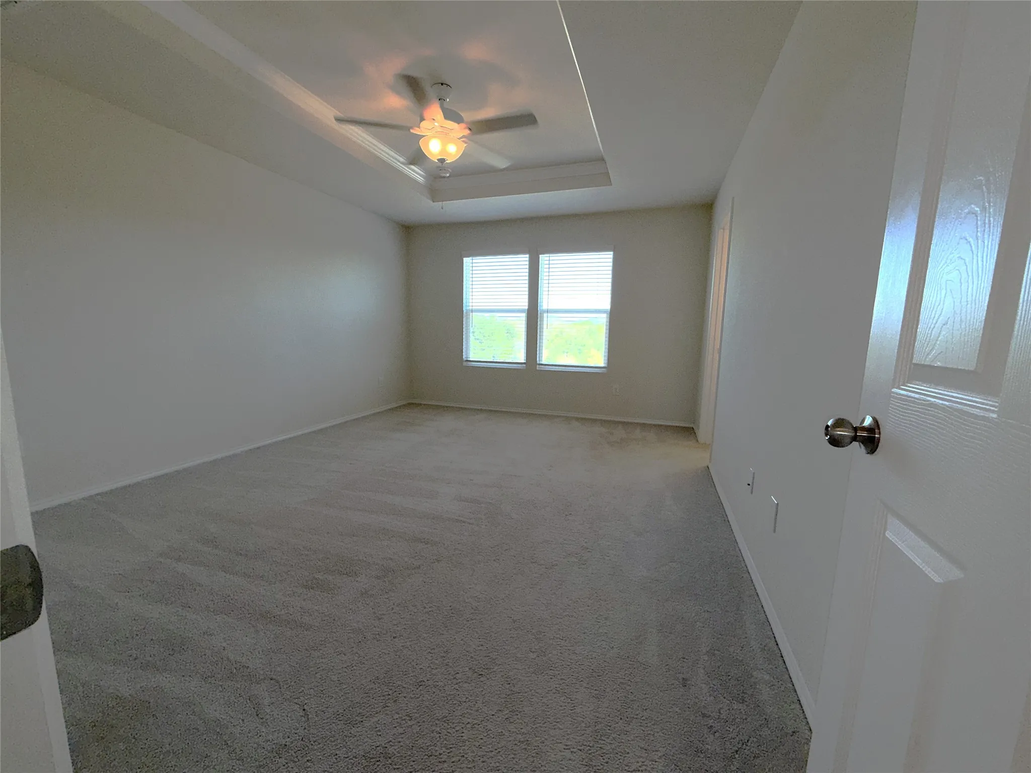 Recessed ceiling with an integrated ceiling fan, light gray carpet flooring, and dual windows with horizontal blinds