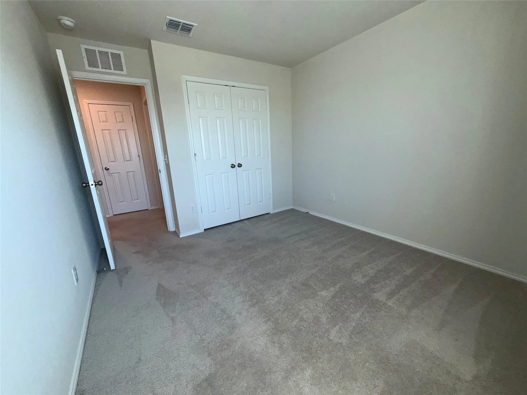 Neutral-toned carpeting with light-colored walls and a bi-fold closet