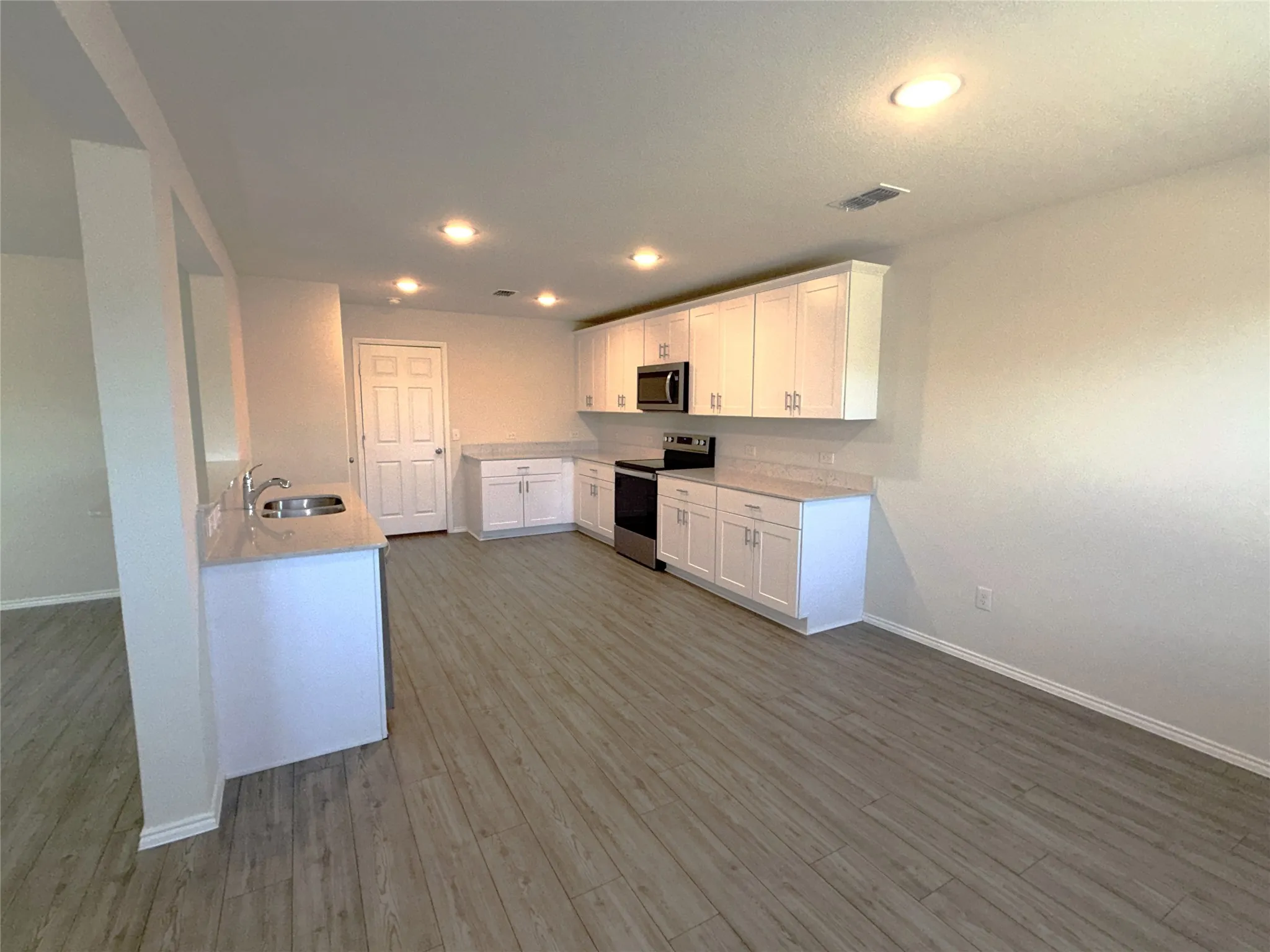 Luxury vinyl plank flooring throughout, complemented by white cabinetry, light-toned countertops, and recessed lighting