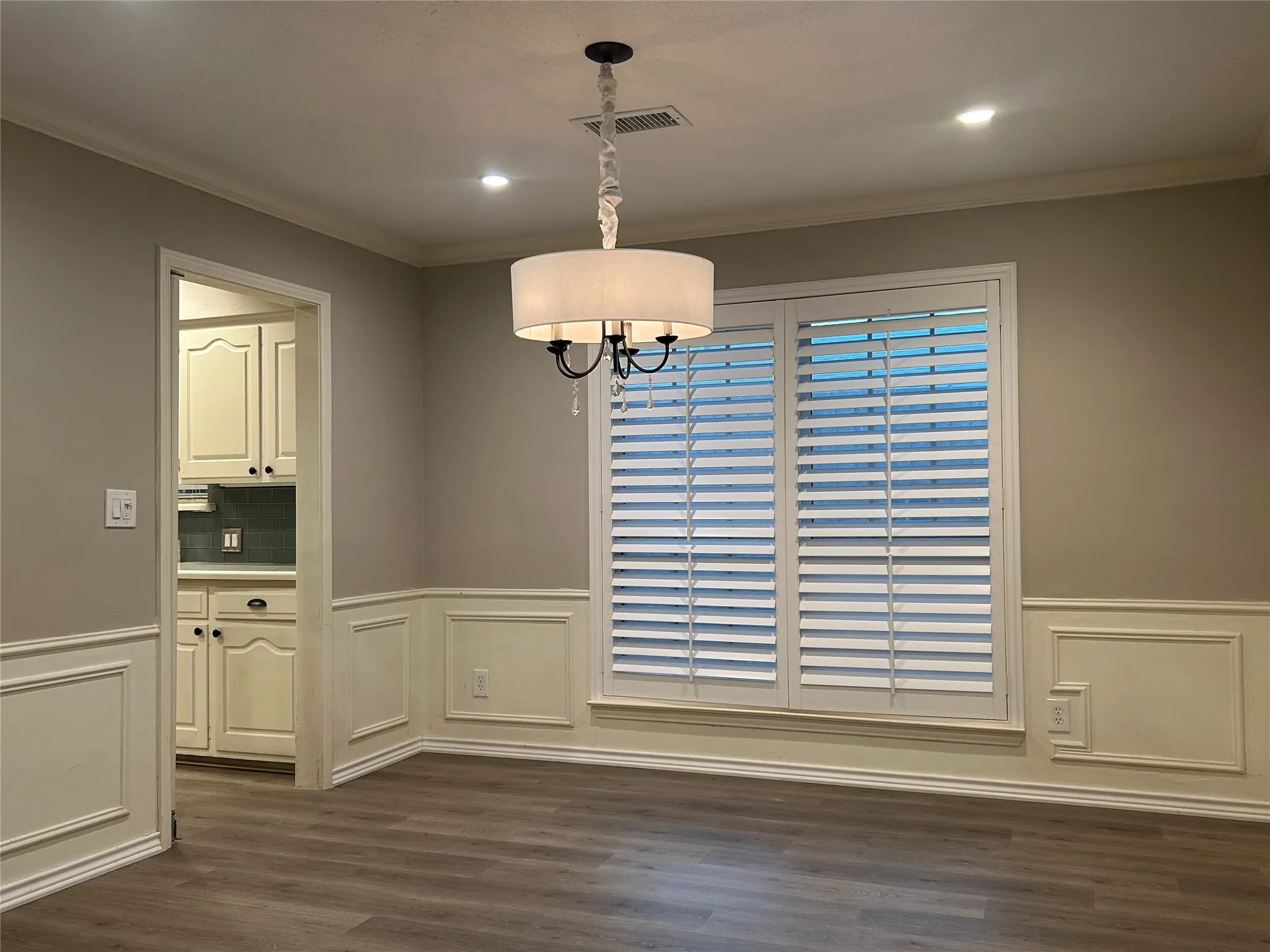 The large dining room which is adjacent to the kitchen is perfect for hosting dinners with friends and family.  The room features wainscotting and crown molding along with plantation shutters.