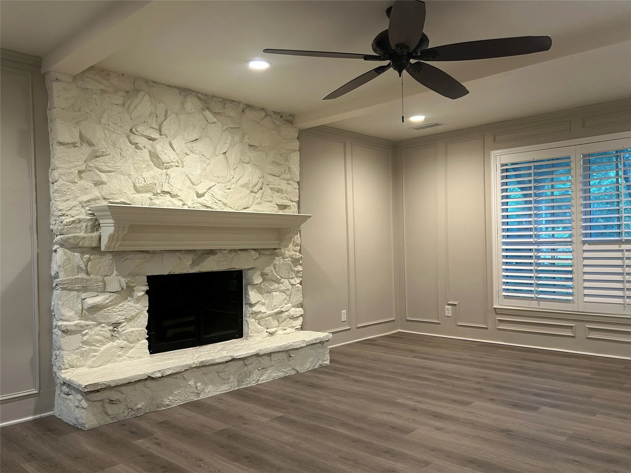 The living room has a ceiling fan, gas fireplace, and ceiling beams making for a warm and inviting entertaining area.