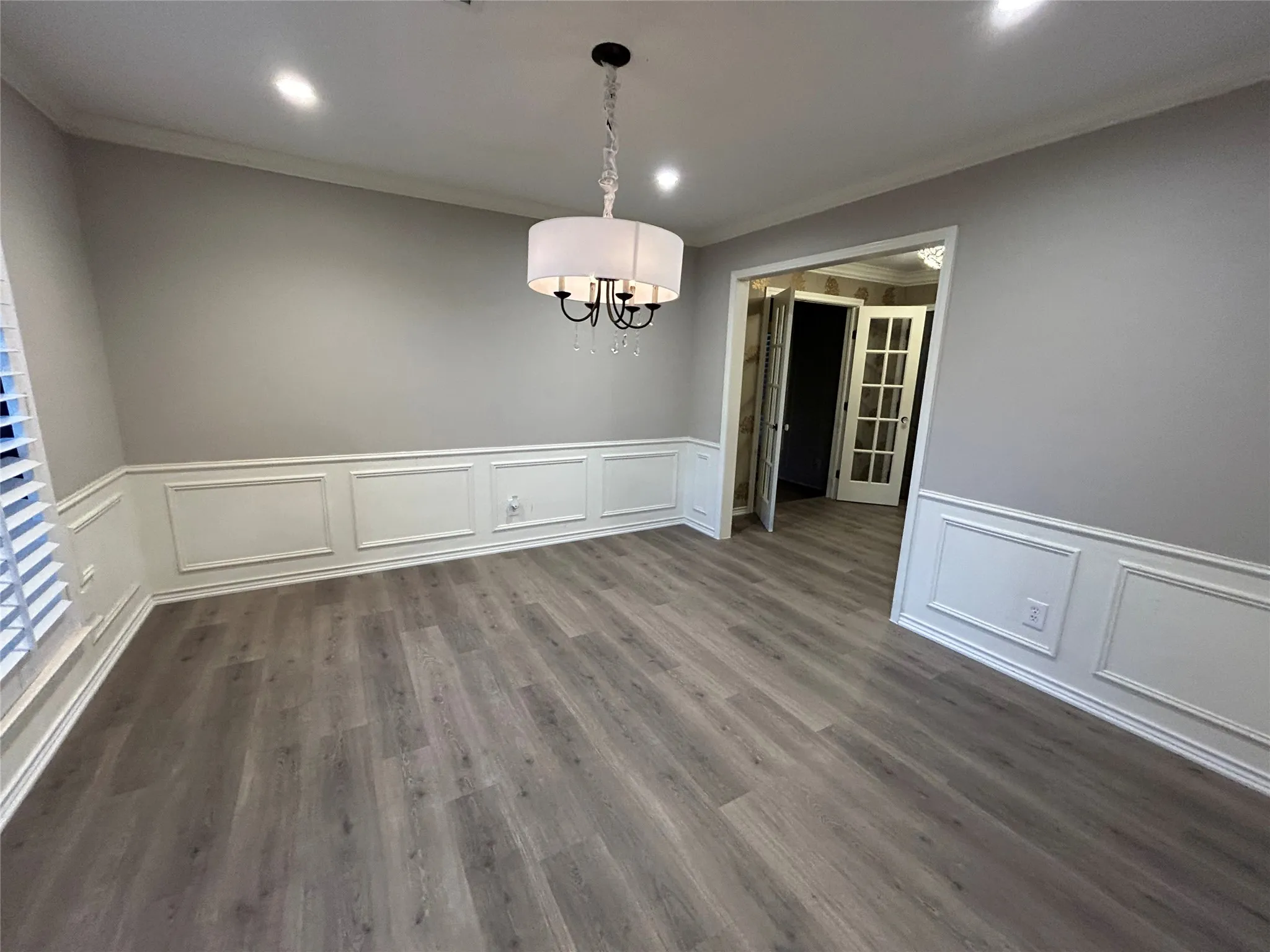The flooring extends throughout the entire level including the living room, kitchen, den, and primary bedroom creating a seamless transition between rooms.