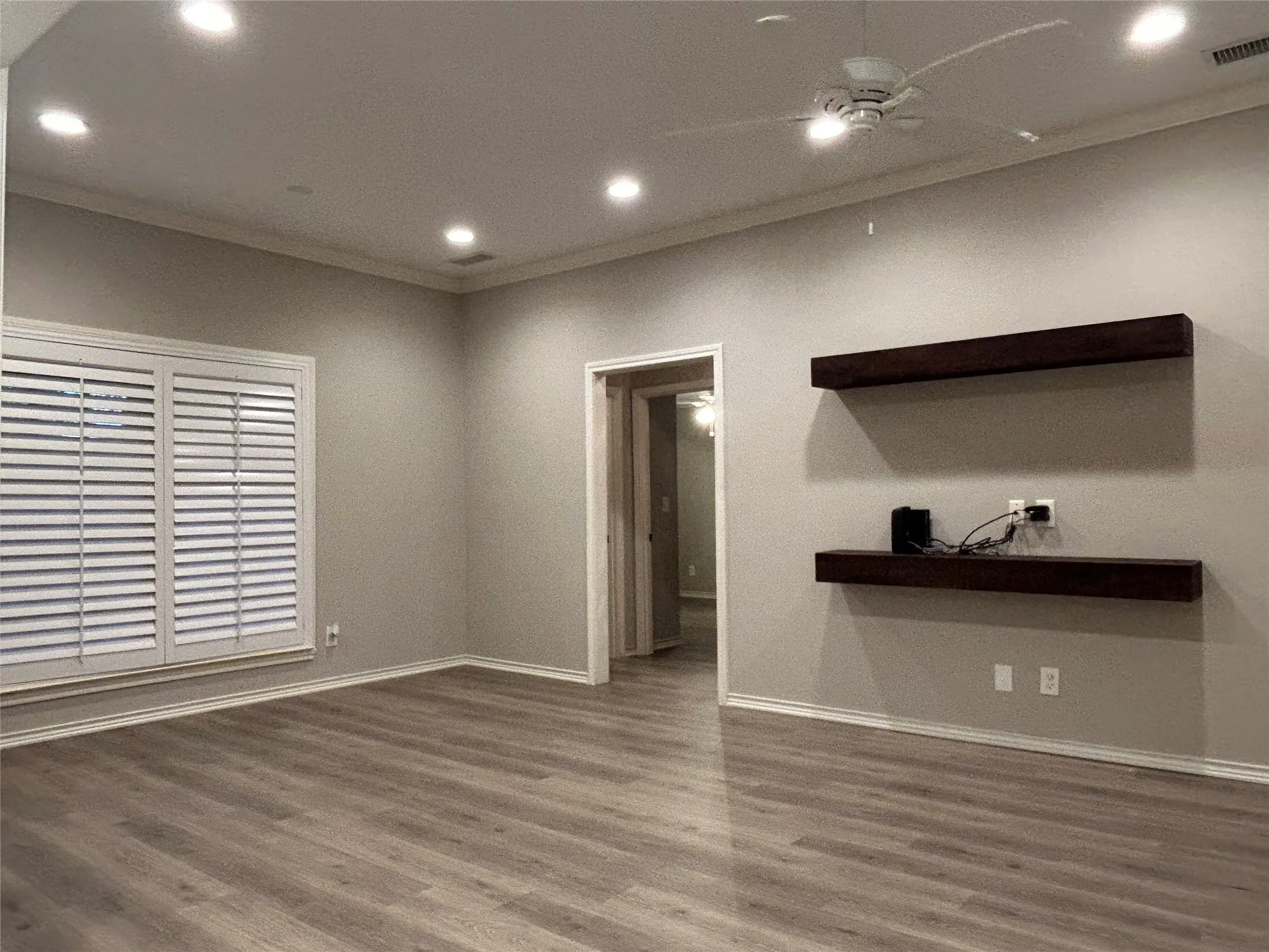 The family room has recessed lighting, crown molding, a ceiling fan, and shelving for a TV and electronics.