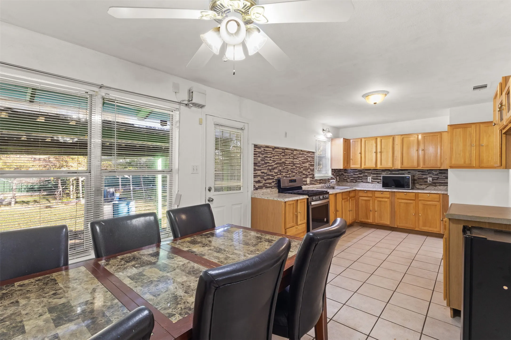 Kitchen with wood-finish cabinetry, tile flooring, and a decorative tile backsplash