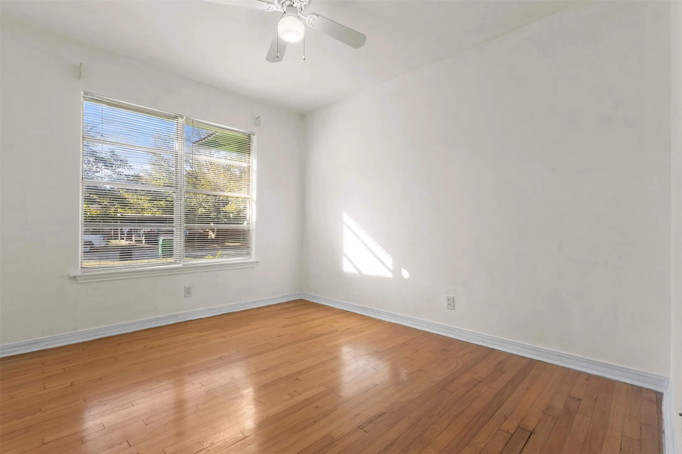 Wood-finish flooring with crisp white walls and a ceiling fan