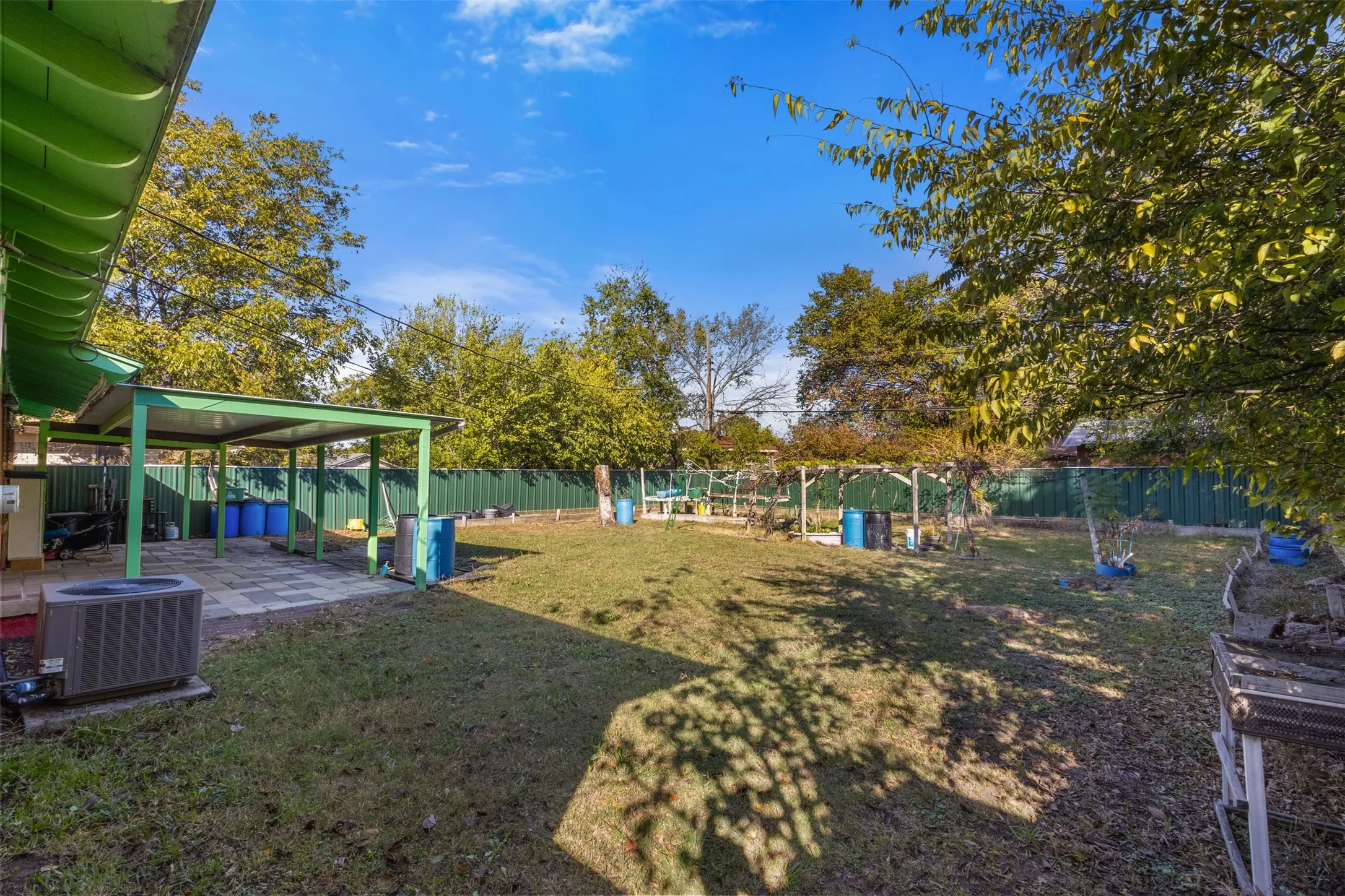 Expansive backyard featuring a covered patio with paved flooring, a spacious lawn area, and a privacy fence