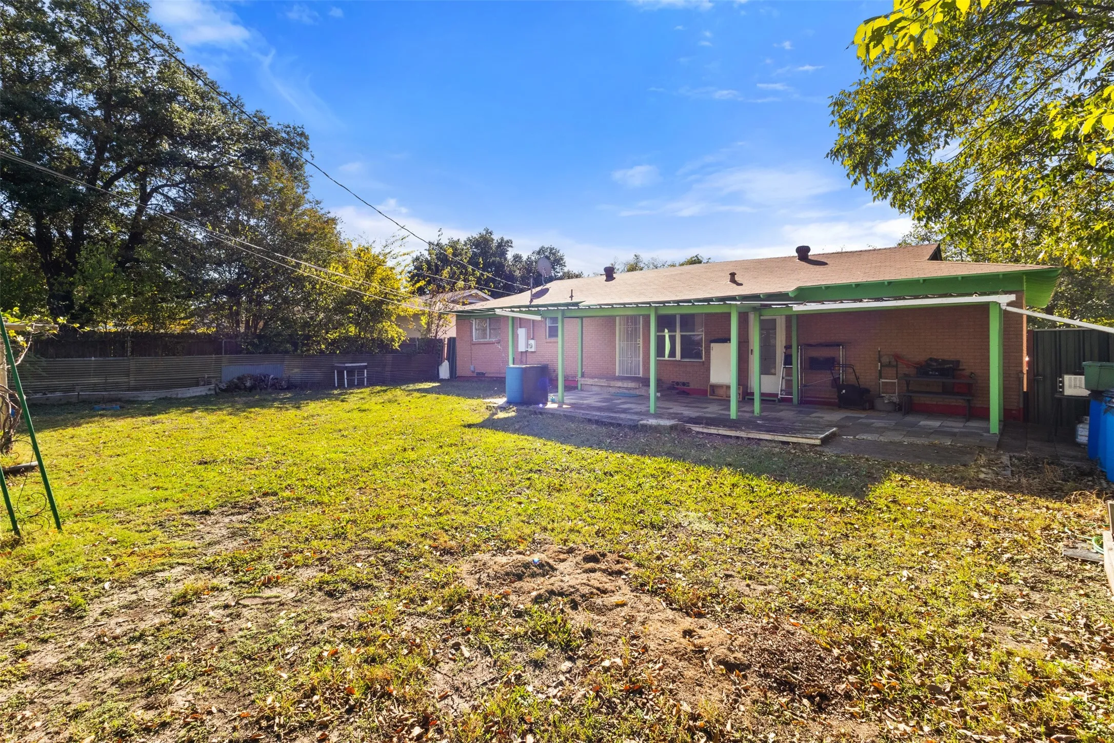 Expansive grassy yard with a covered patio area and partial fencing