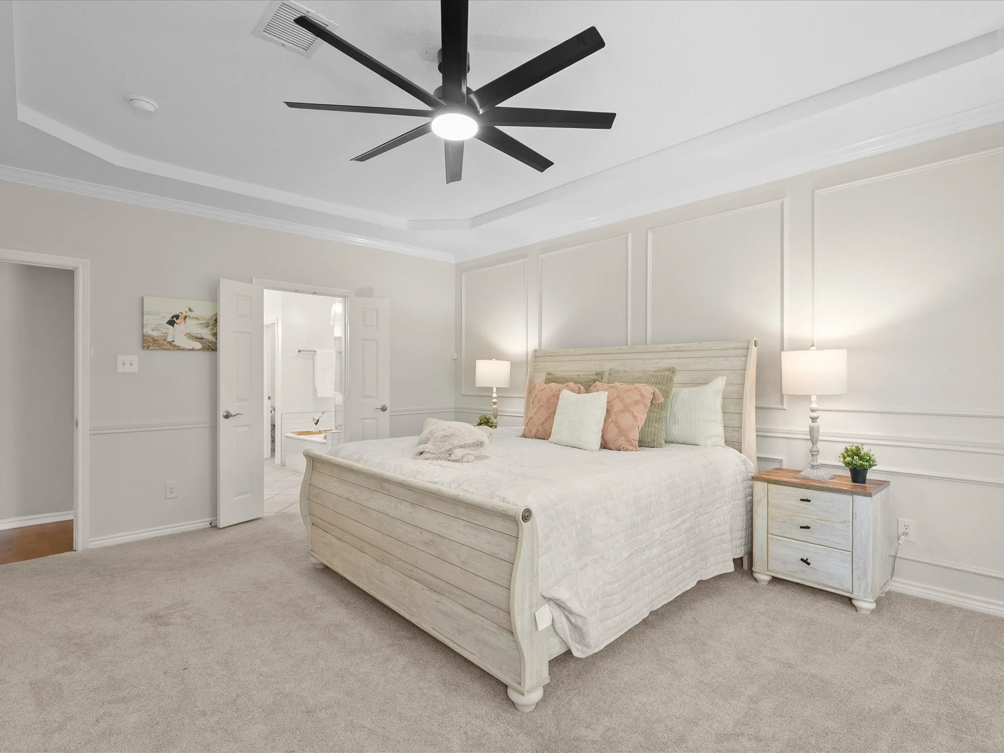 Tray ceiling with crown molding, ceiling fan with integrated lighting, wainscoting accent wall, carpeted flooring, and a double door entry