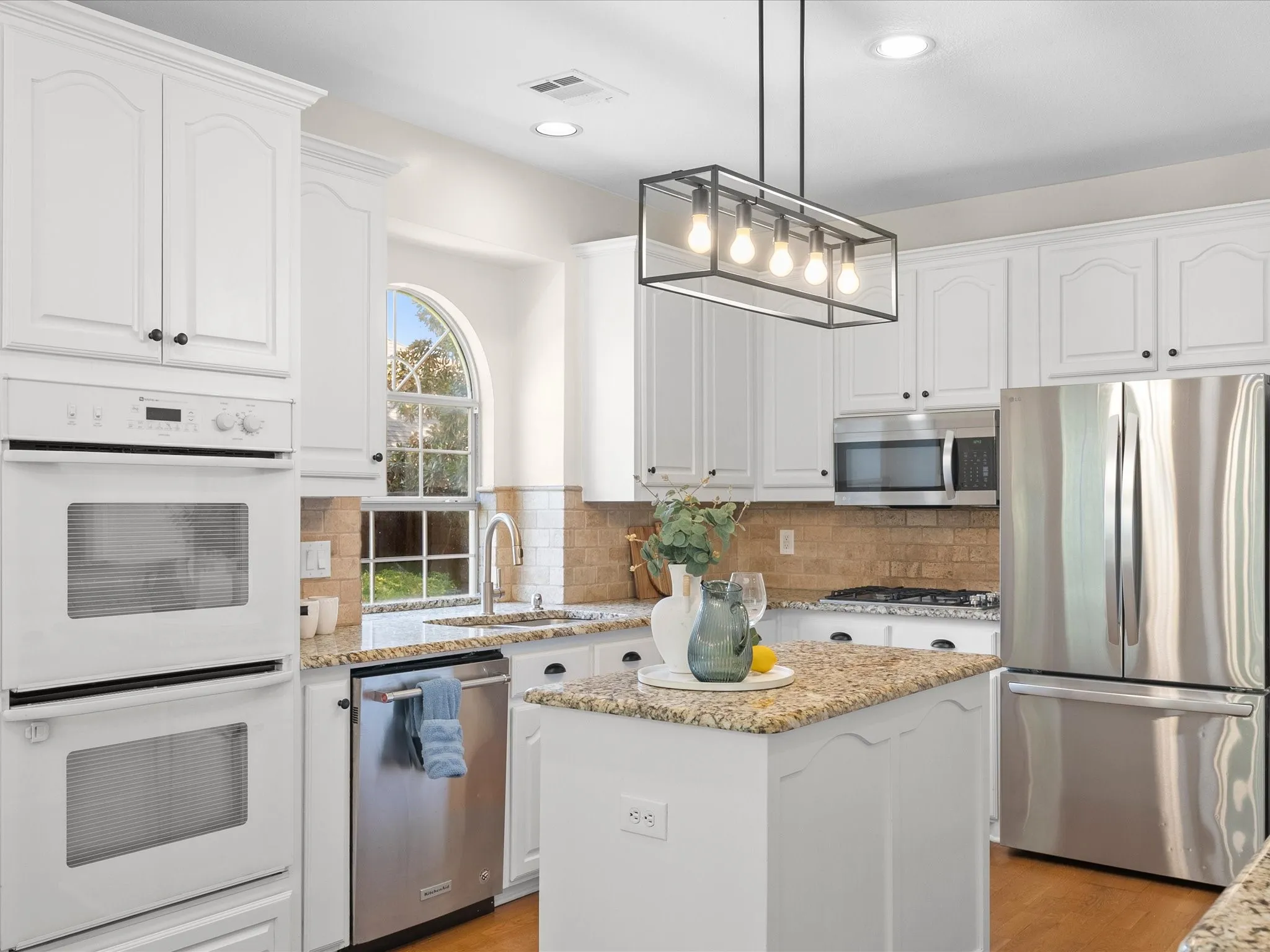 White cabinetry, stainless steel appliances, granite countertops, and a tile backsplash