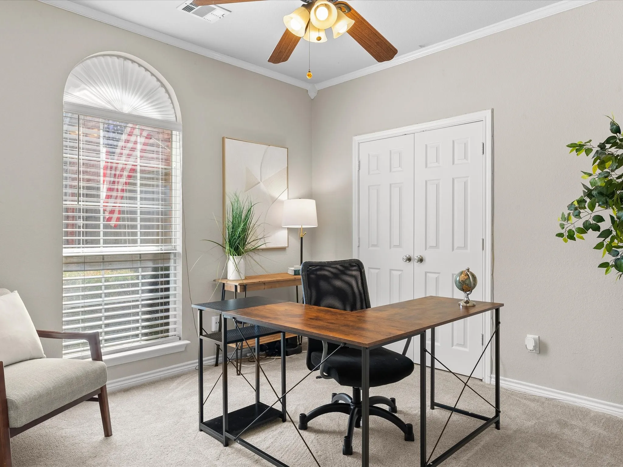 Arched window with blinds, wood-finish ceiling fan, neutral wall paint, white trim, and carpet flooring