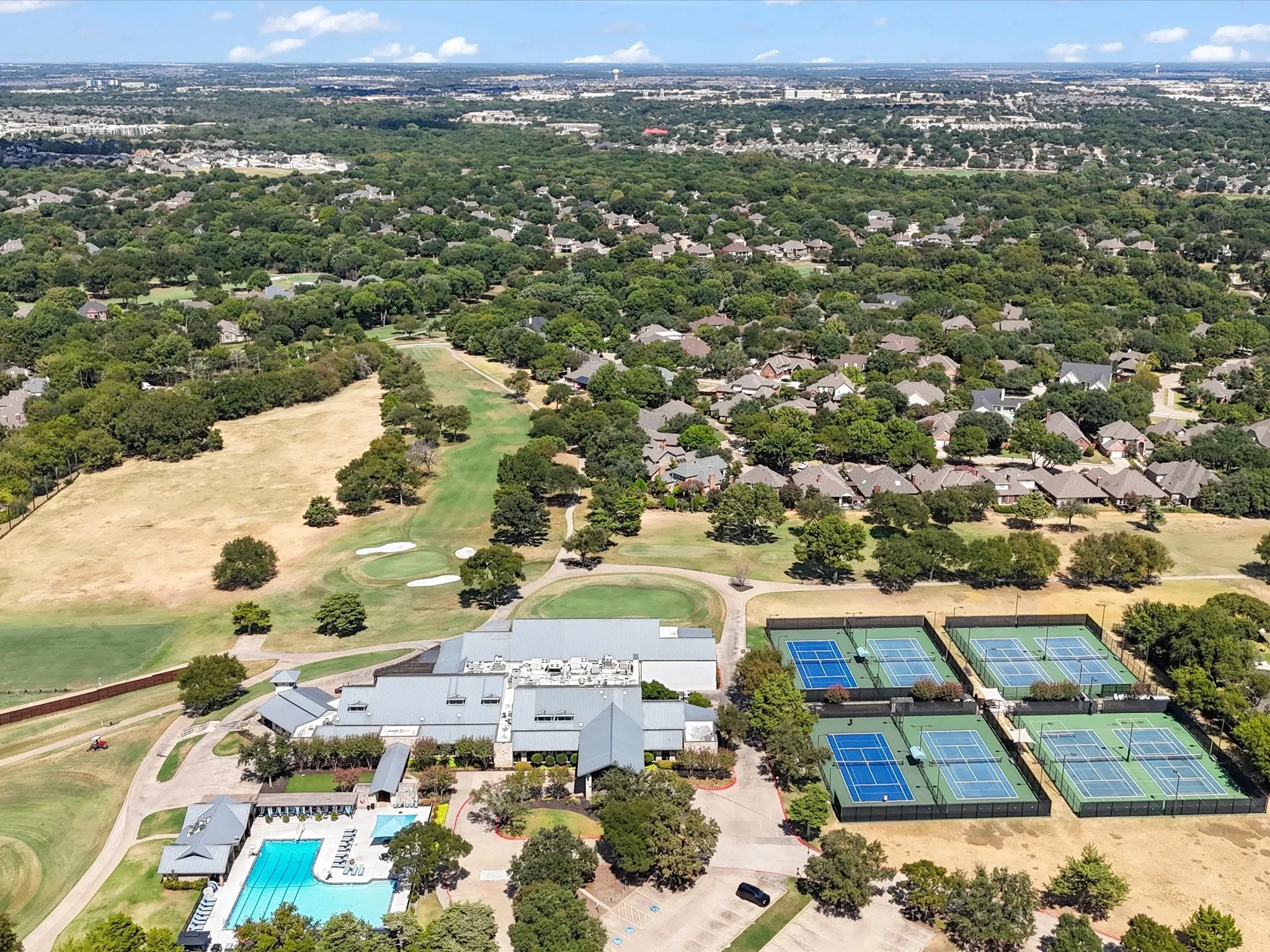 Aerial perspective showcasing the golf course, tennis courts, and swimming pool within the community
