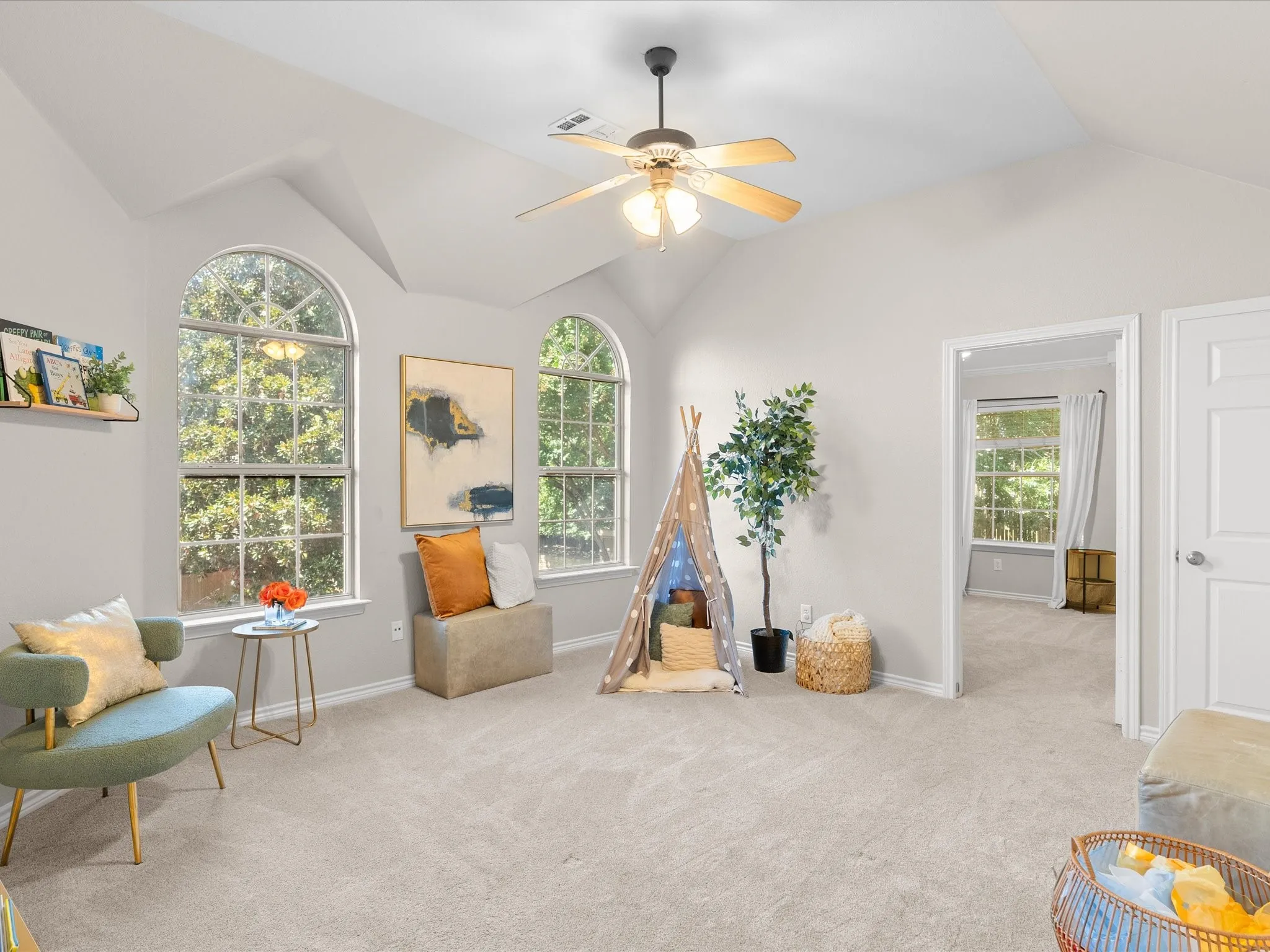 Arched windows, vaulted ceiling, ceiling fan, neutral carpet, and an interior doorway