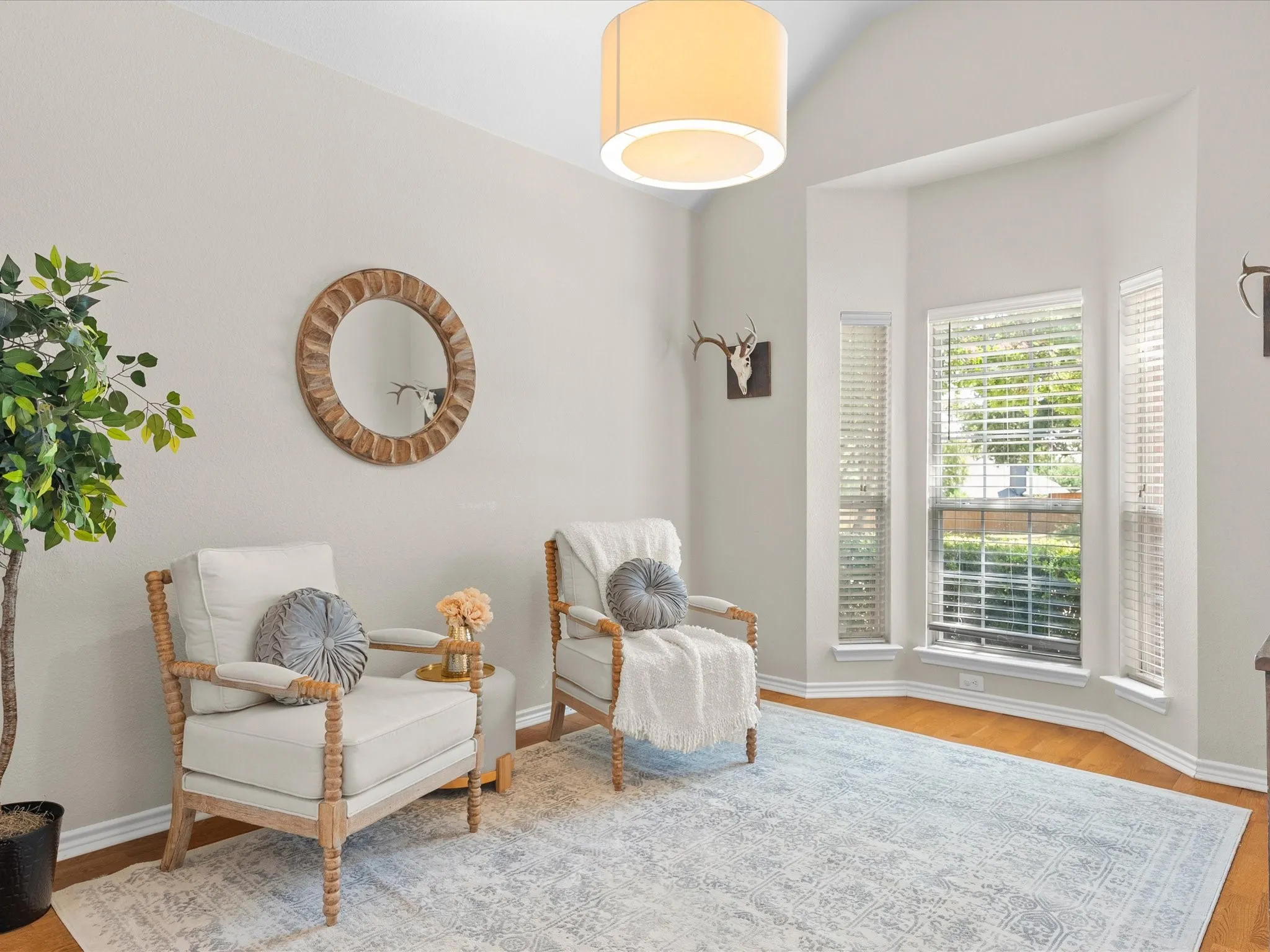 Vaulted ceiling, wood-finish flooring, bay windows, drum pendant light, and neutral wall tones