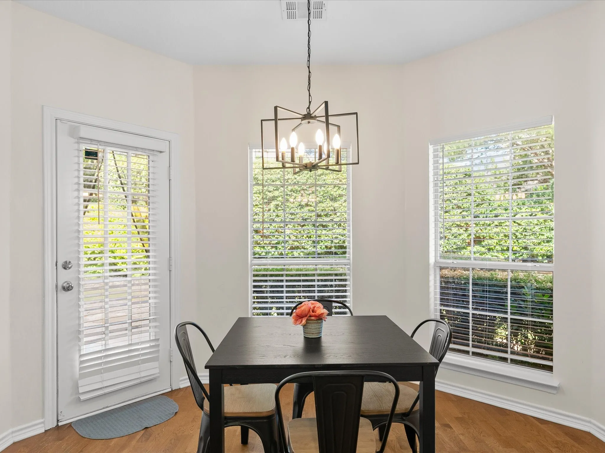 Recessed bay window area with wood-finish flooring, a modern geometric chandelier, and white wall paint