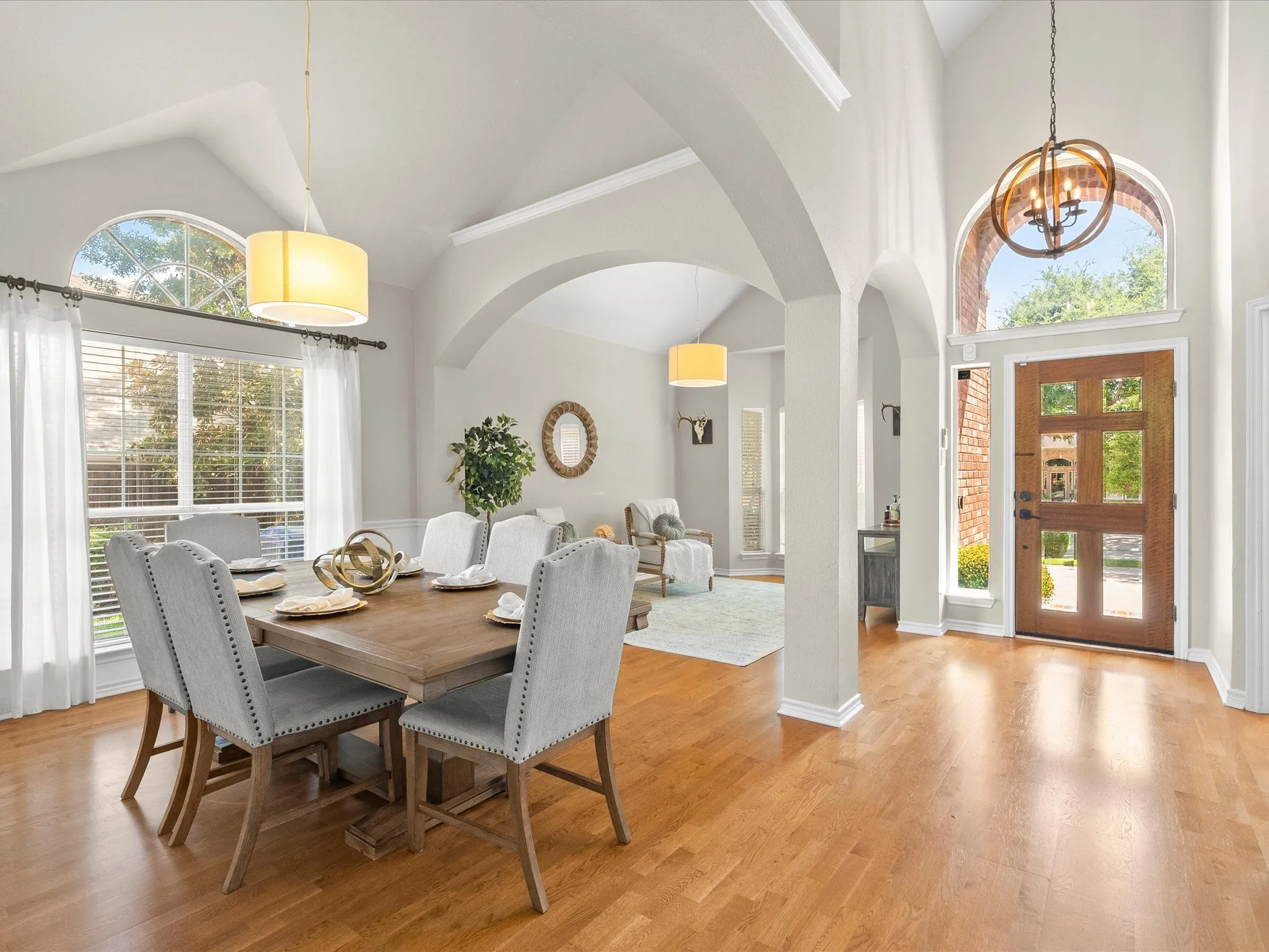 Vaulted ceilings, wood-finish flooring, arched doorways, a wood-panel entry door, and a transom window