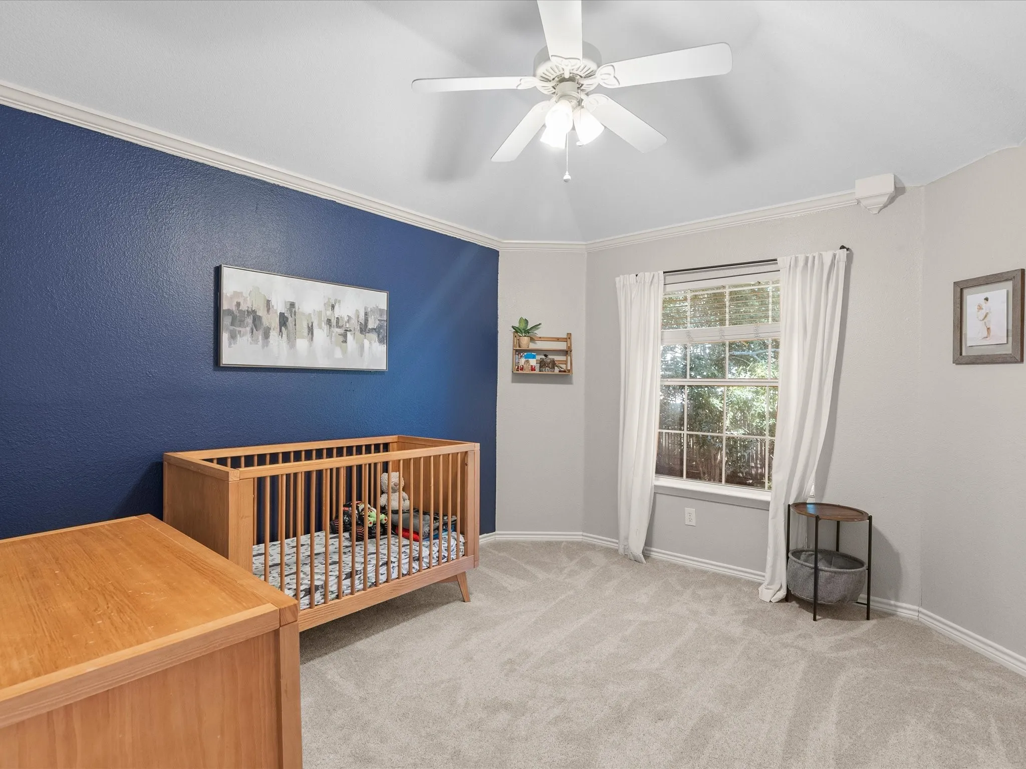 Vaulted ceiling with a ceiling fan, carpeted flooring, and crown molding