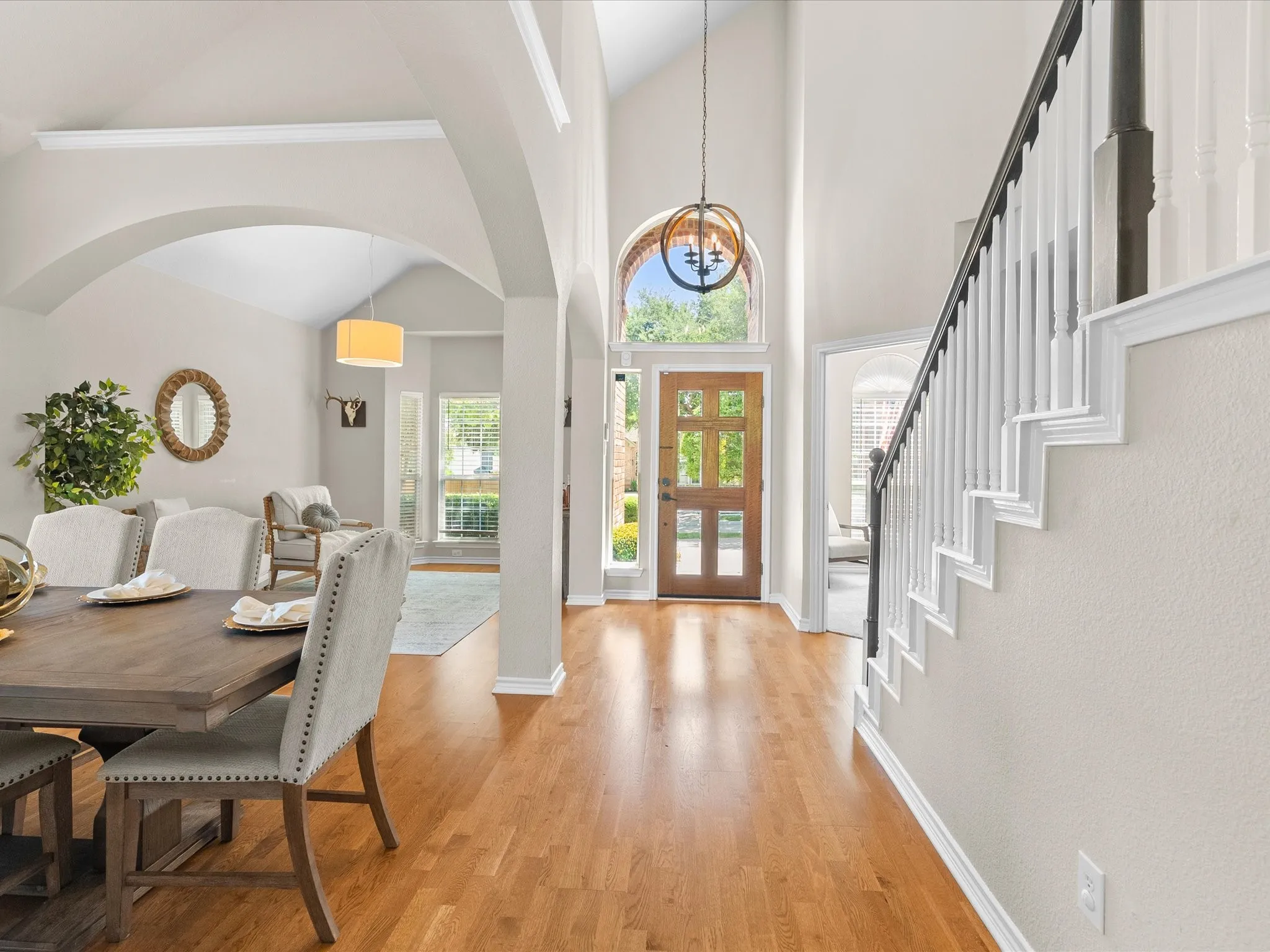 Two-story foyer with a natural wood front door, arched transom window, and a decorative chandelier