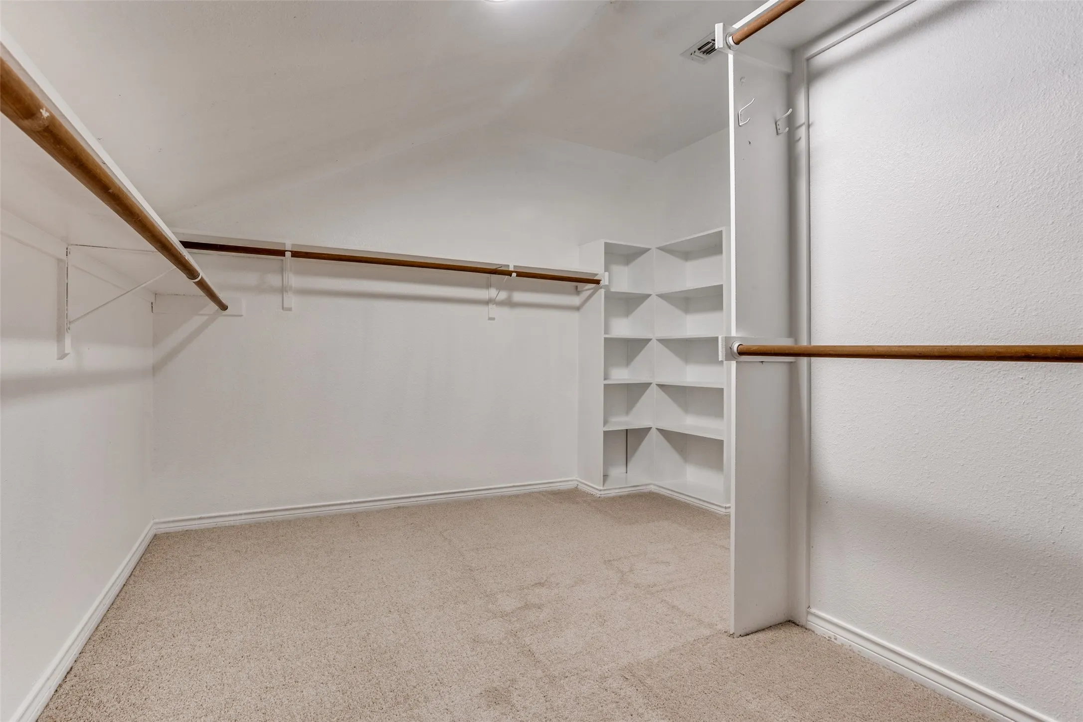 Wall-to-wall carpeting with built-in shelving, two levels of hanging rods, and an additional hanging rack