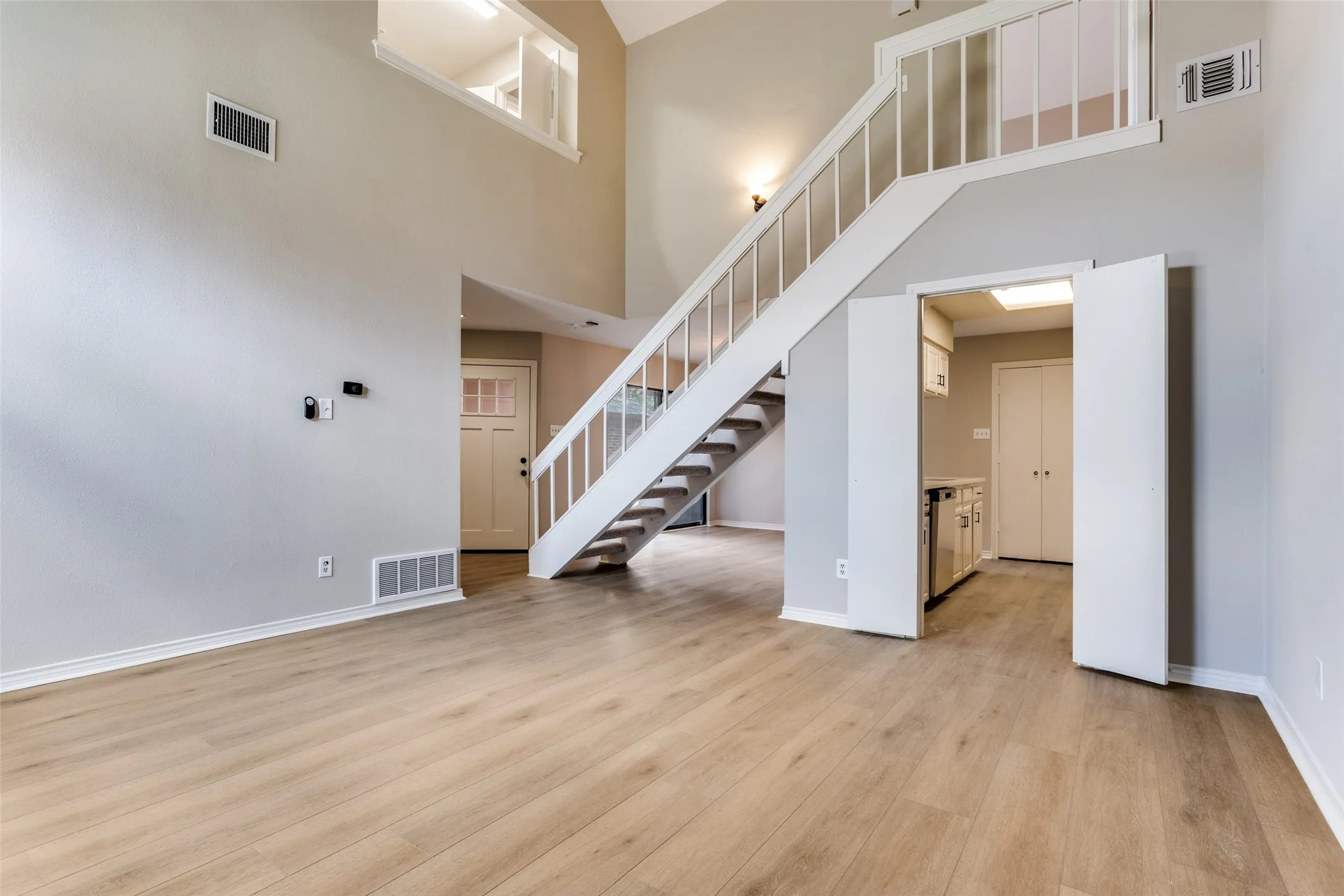 Vaulted ceiling with an open loft, wood-finish flooring, two-story walls, and a built-in staircase