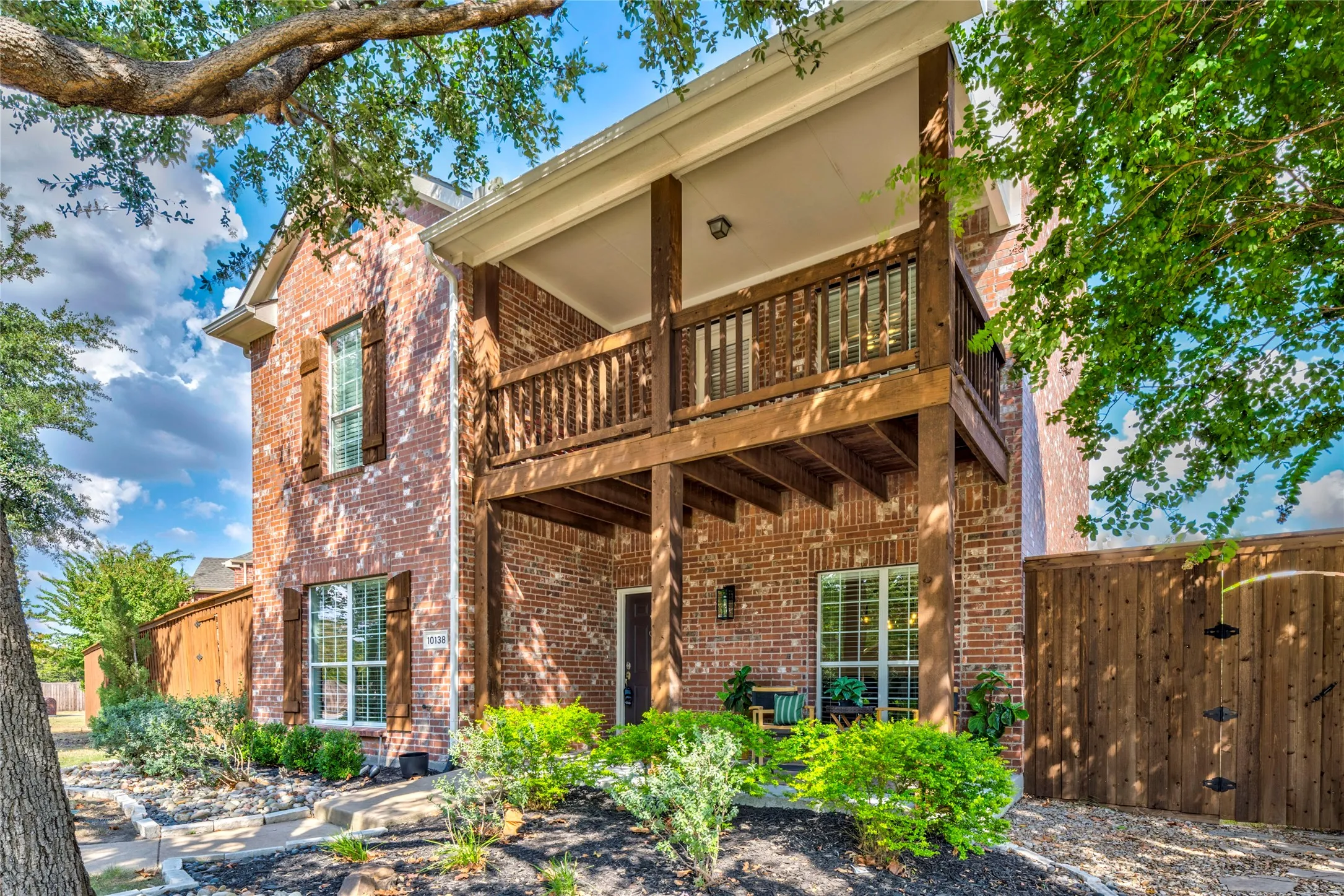 Brick construction, mature trees, and a covered upstairs balcony give this West Frisco home classic curb appeal.