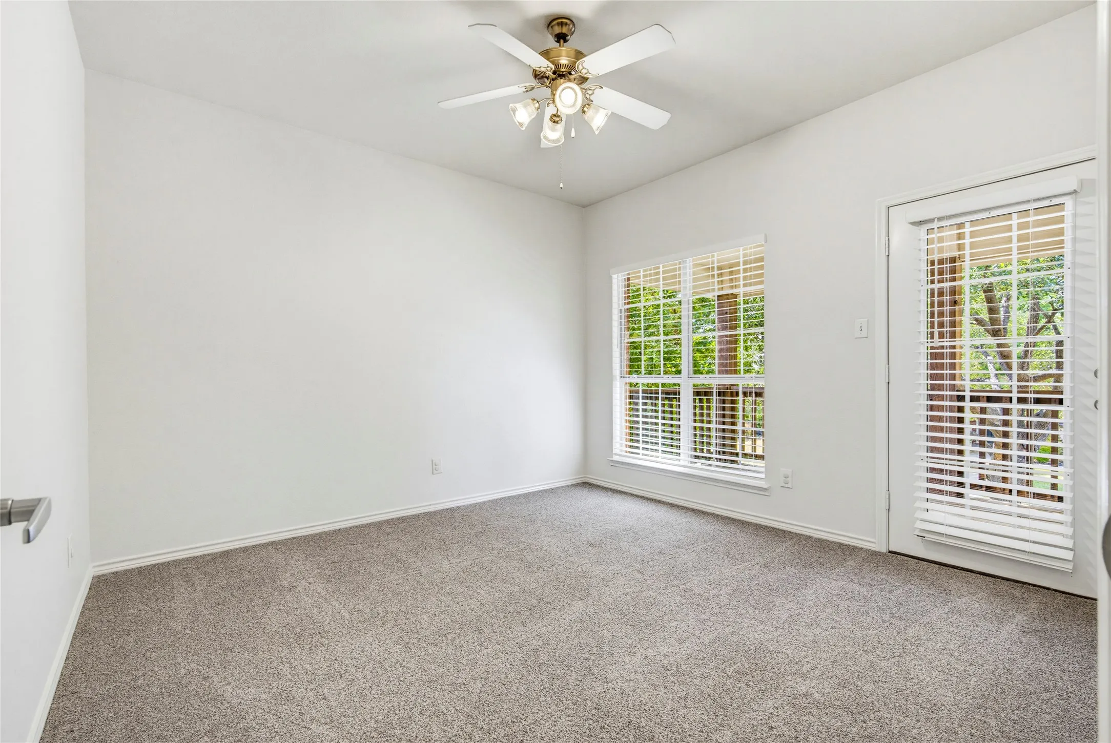 Recent carpet, a ceiling fan, and natural light, and this bedroom opens to its own private covered balcony.