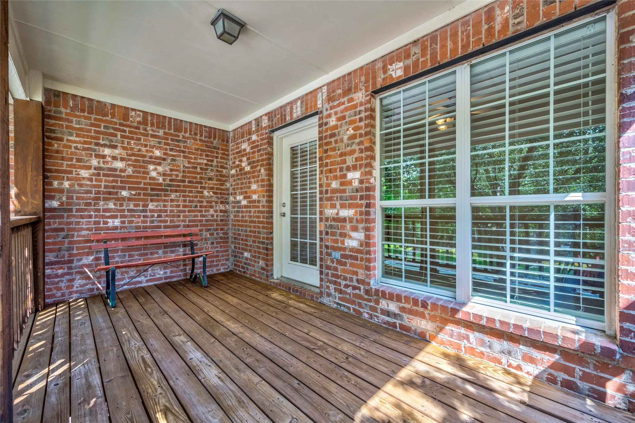 Brick walls, wood decking, and a covered ceiling create a cozy outdoor retreat right off the upstairs bedroom.

