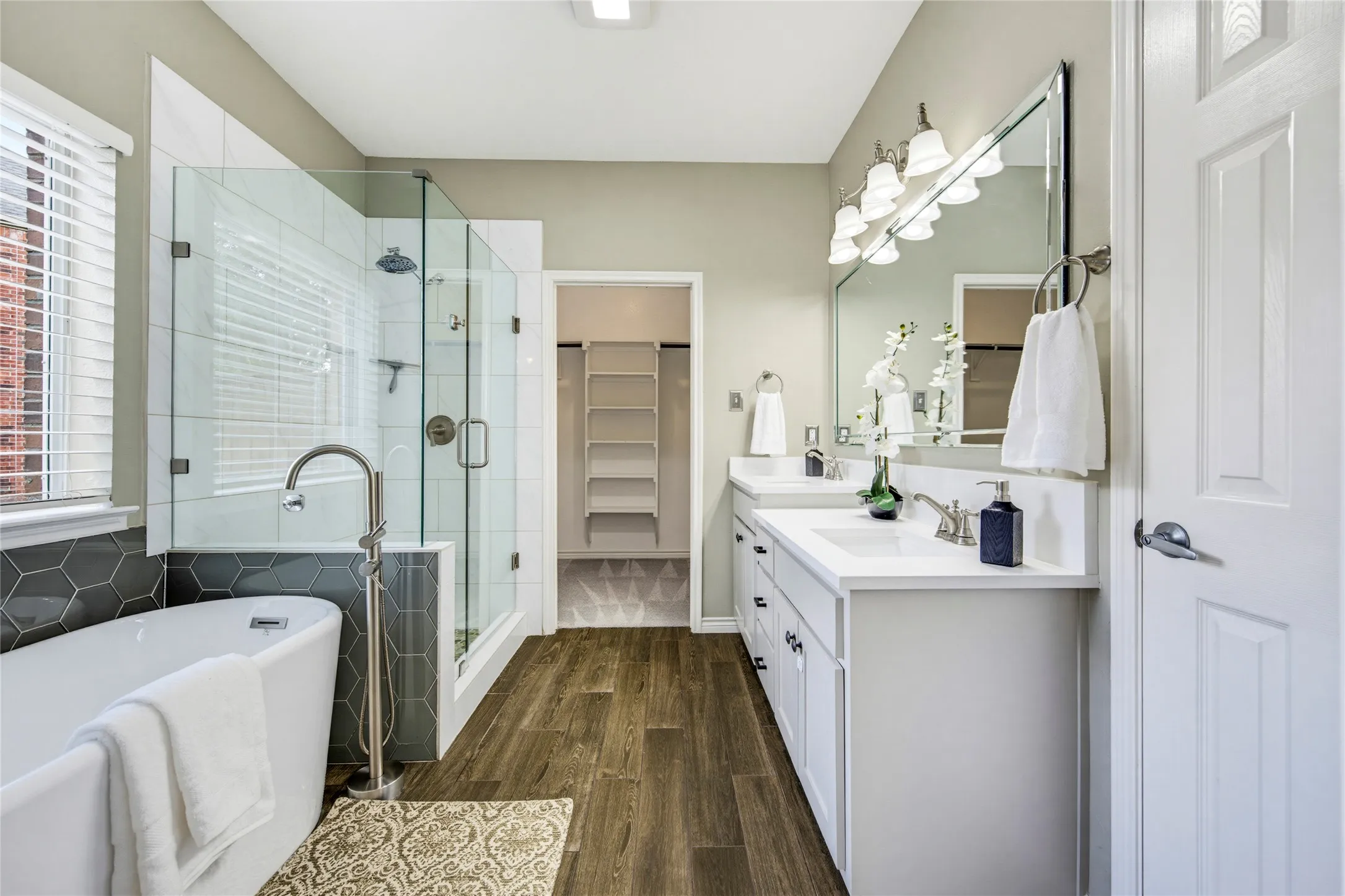 A free-standing soaking tub, frameless glass shower, and walk-in closet turn the everyday routine into a spa-worthy moment.
