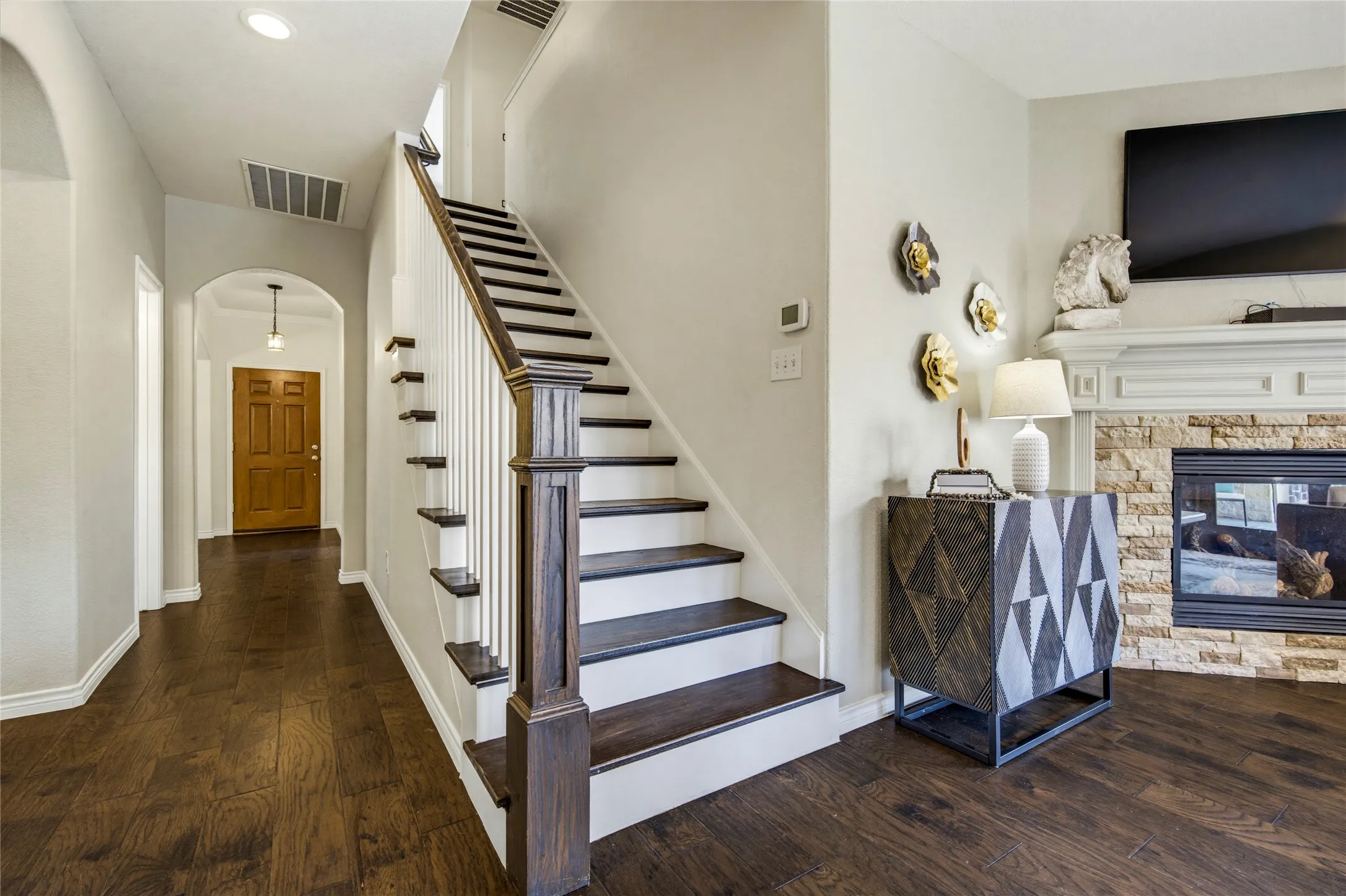 Hardwood stair treads with crisp white risers lead upstairs to the game room, home office, and secondary bedrooms.
