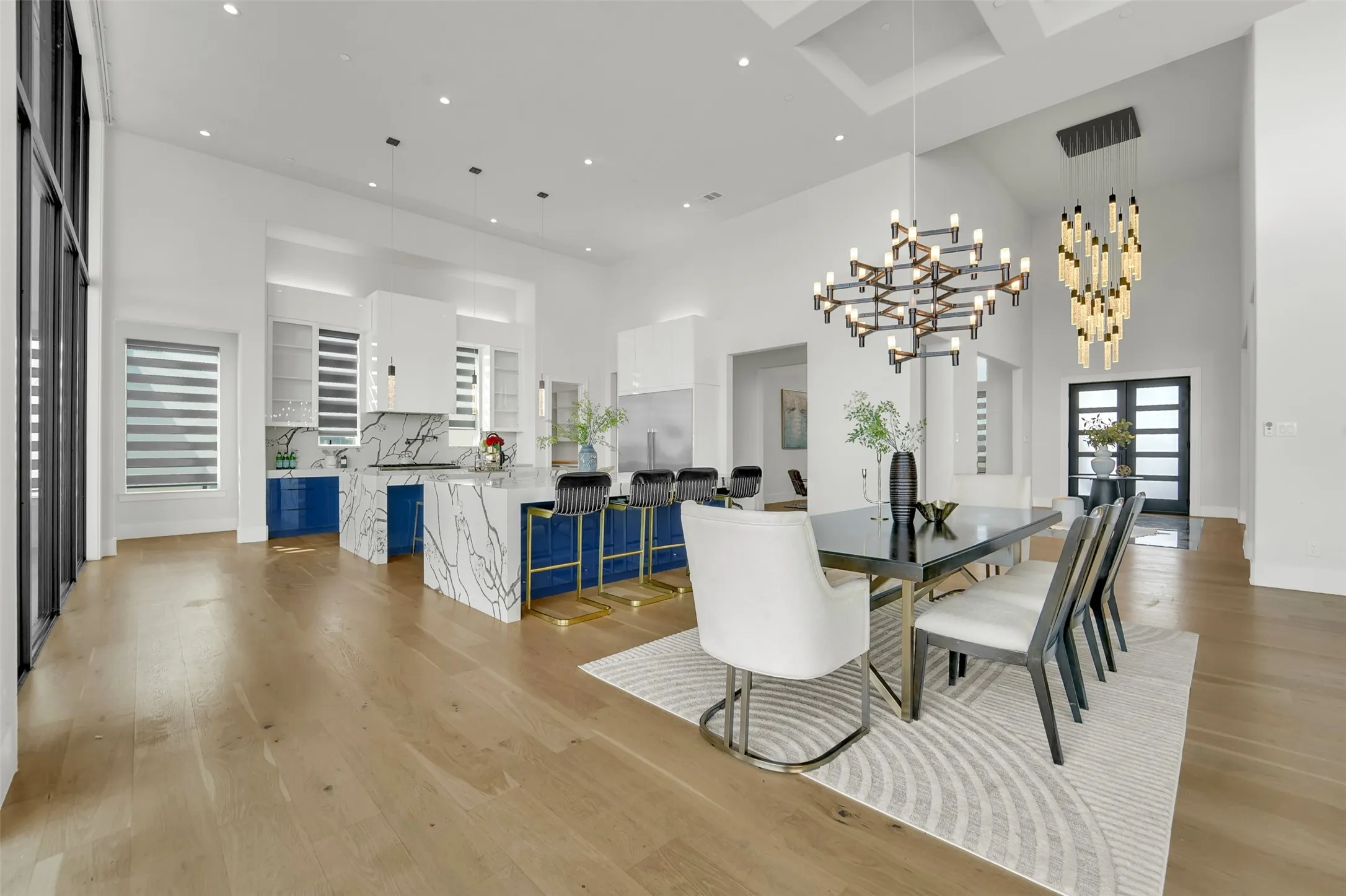 High ceilings with recessed lighting, light wood-finish flooring, and a kitchen island with a waterfall countertop