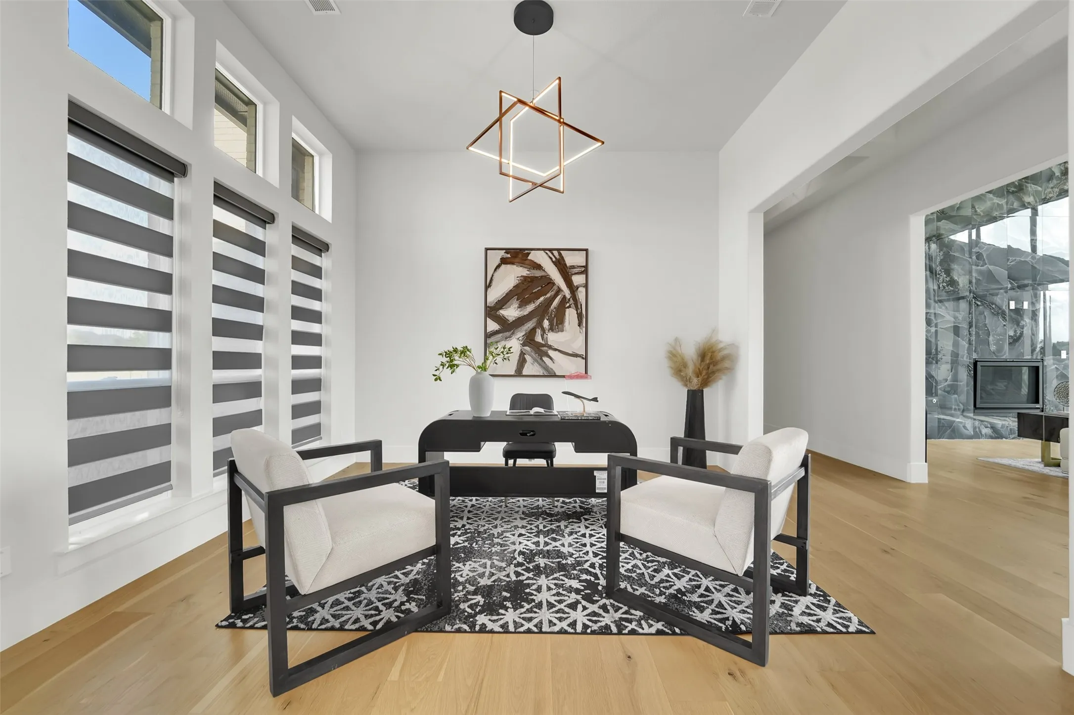 Wood-finish flooring, high ceilings, expansive windows with integrated window treatments, and a contemporary light fixture