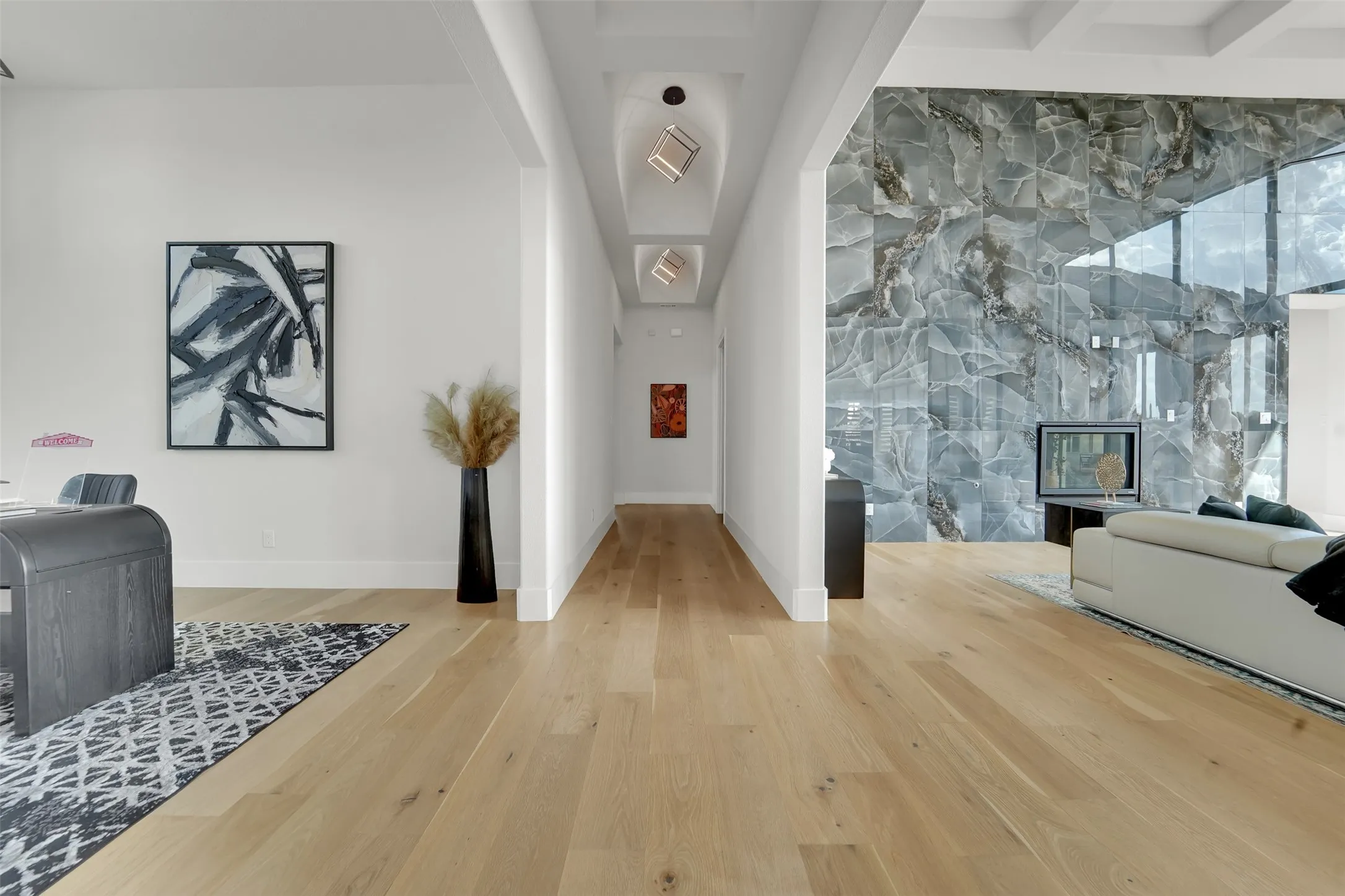 Wood-finish flooring throughout, tray ceiling with recessed lighting, stone-clad accent wall, and a built-in fireplace