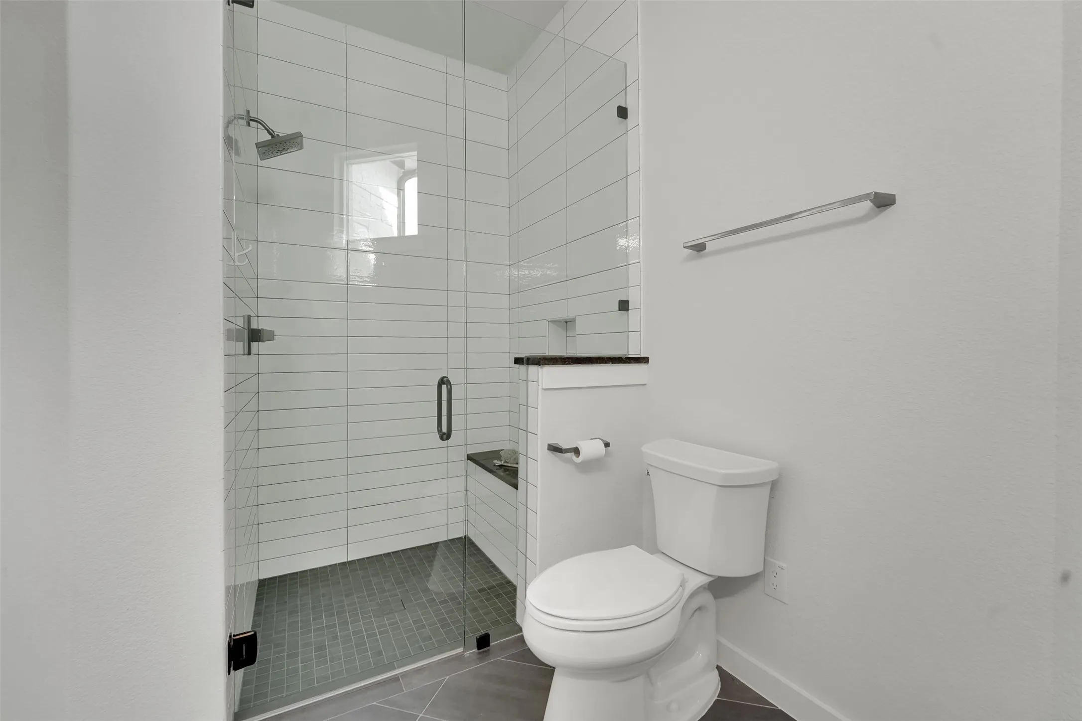 Glass-enclosed shower with subway tile surround, built-in bench, and a rain shower head