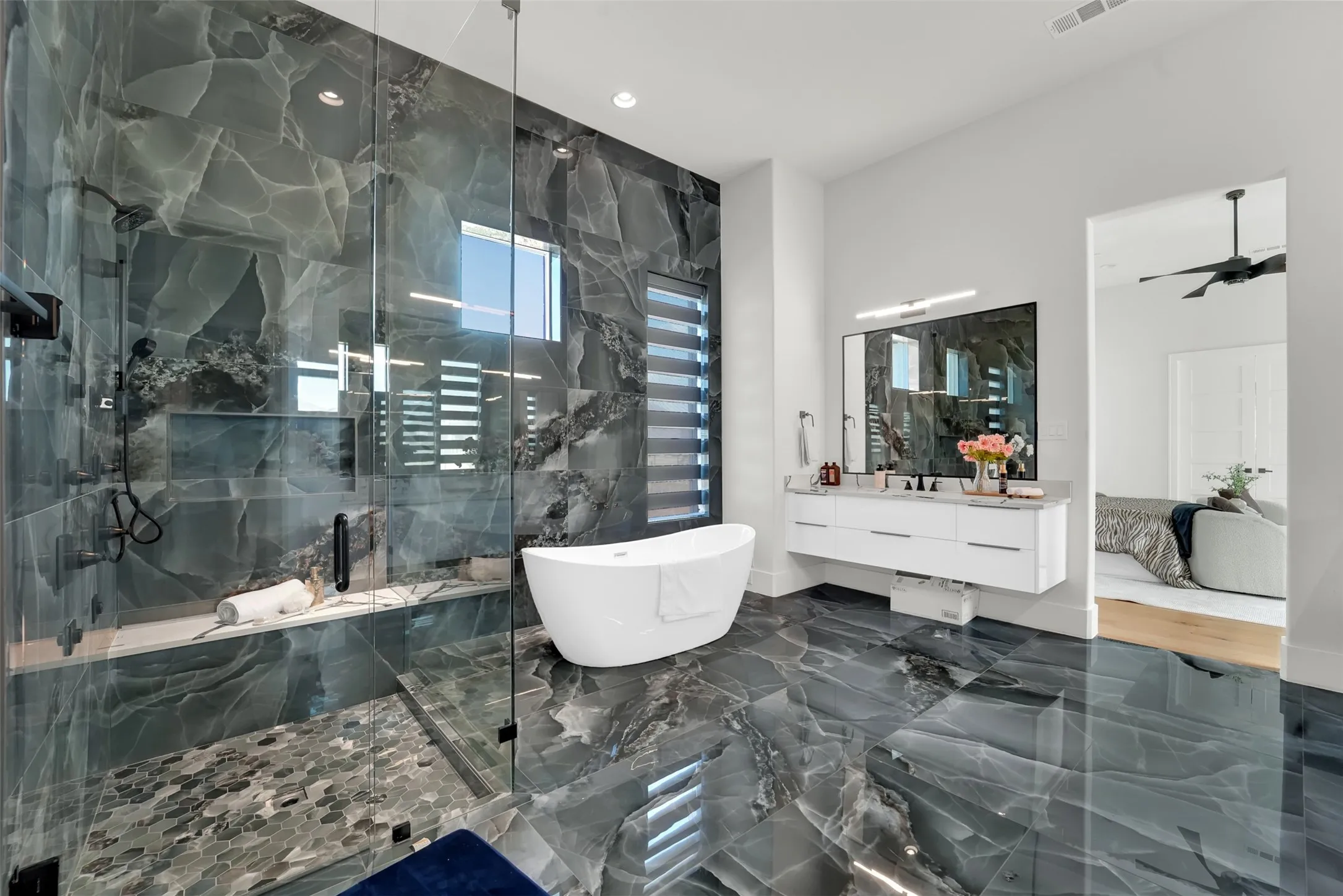 Glass-enclosed shower with stone tile walls, a built-in bench, and a recessed niche